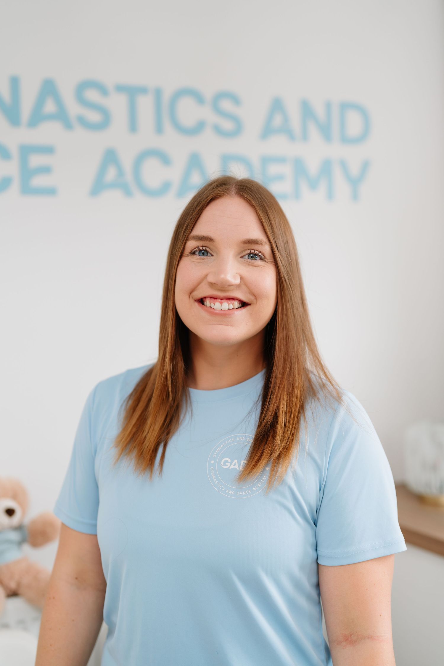 Dance instructor wearing light blue uniform shirt poses at gymnastics academy. Manningtree, Essex.