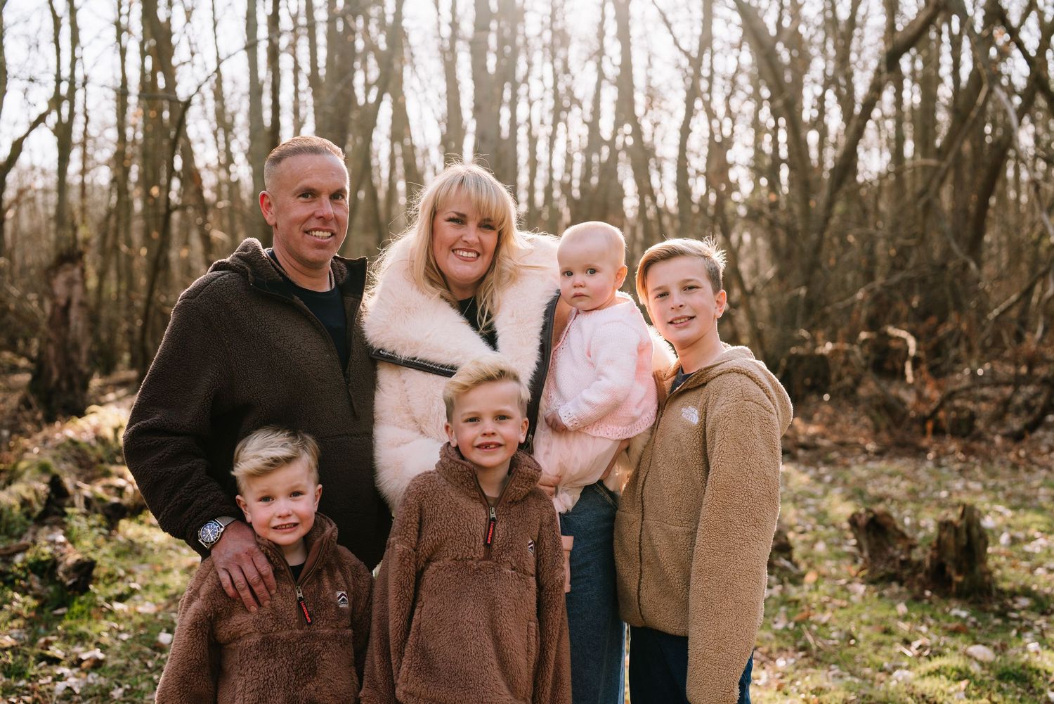 Family portrait session in a wooded area during autumn with fallen leaves on the ground. Wrabness Woods, Essex.