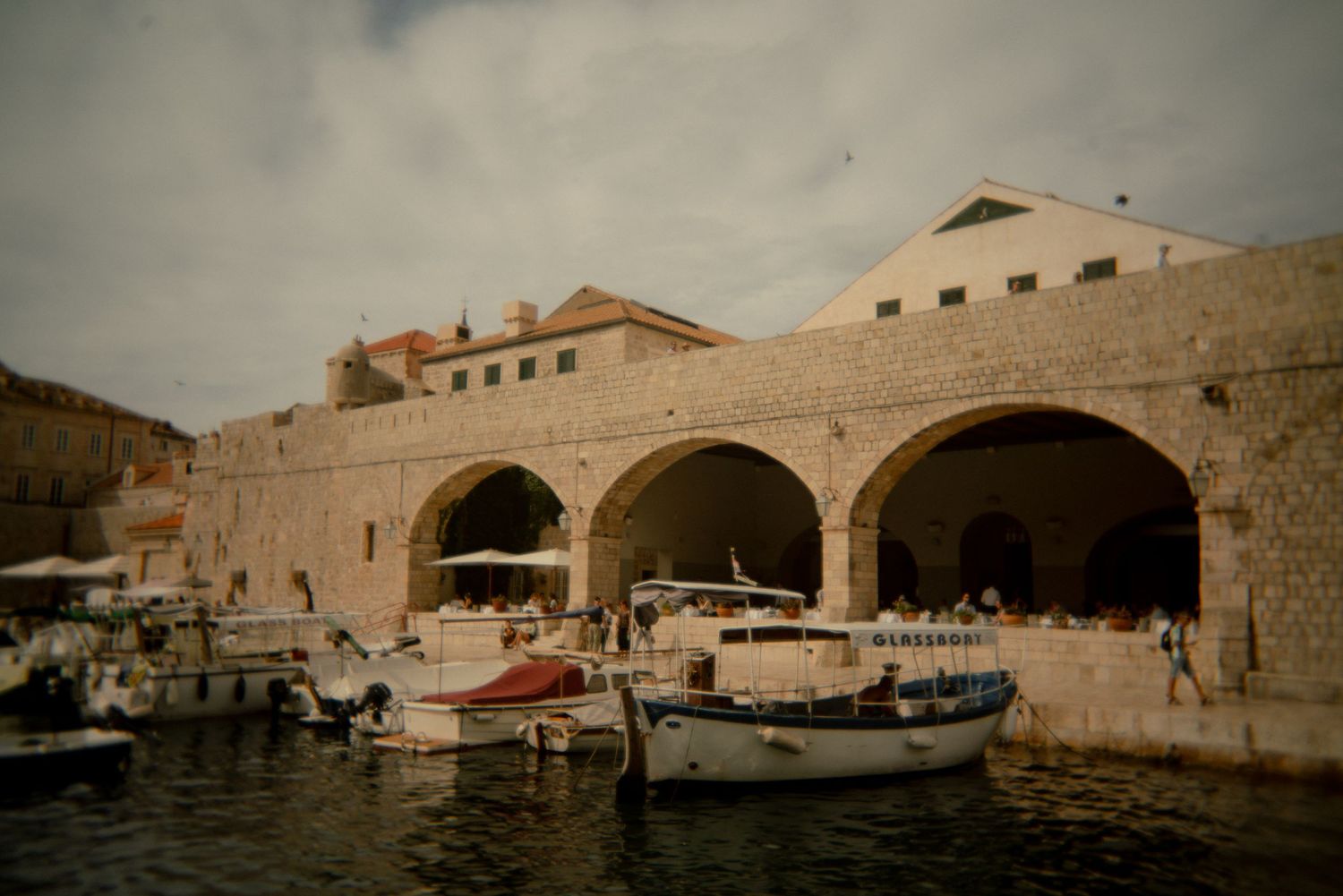 Historic stone harbor with boats docked along a Mediterranean waterfront. Croatia.