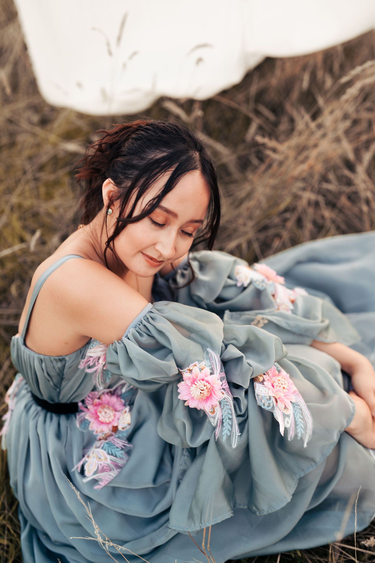 Ethereal fashion photography of a flowing blue dress with pink flowers against a natural backdrop. Wrabness, Essex.