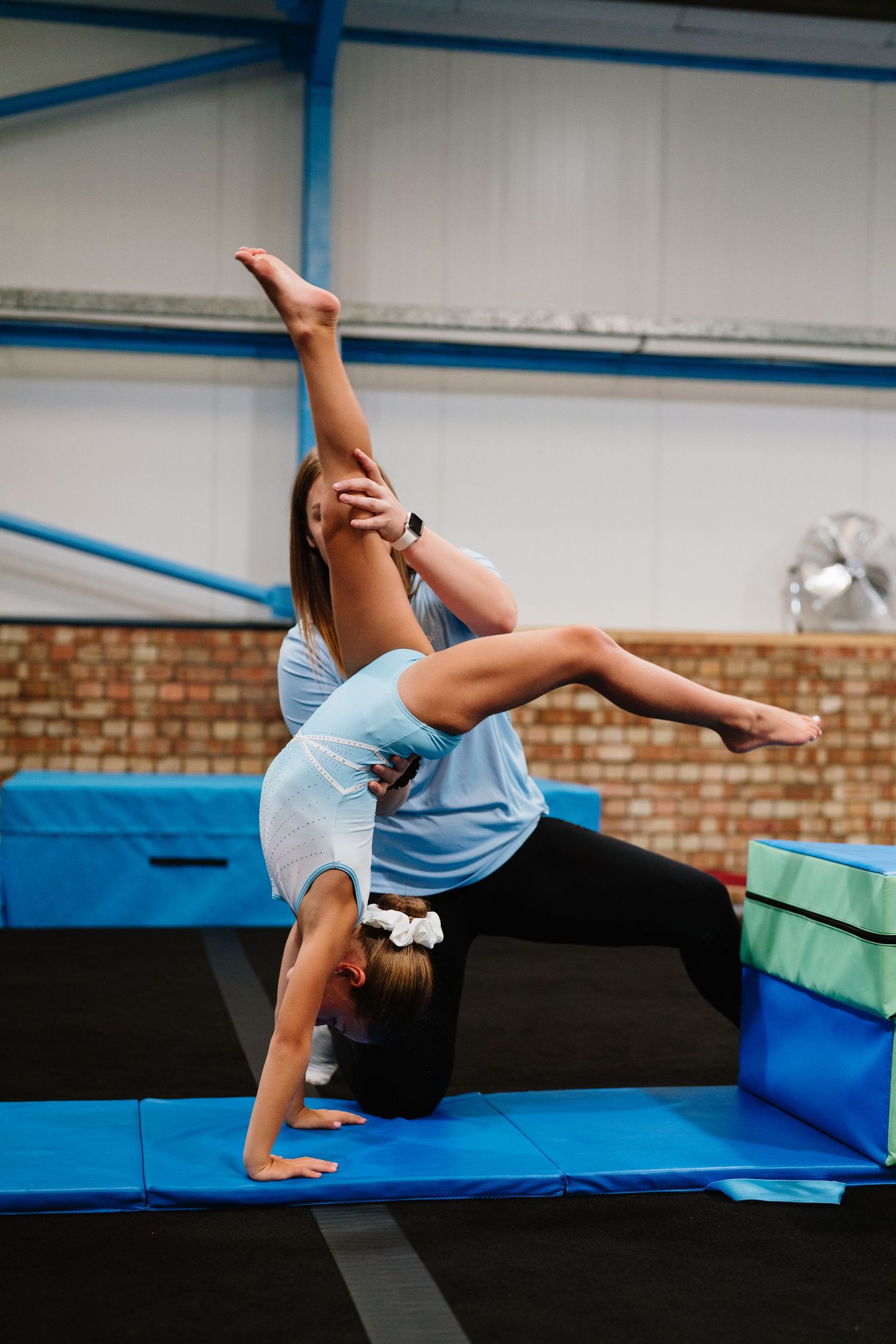 Gymnast performing back handspring sequence on blue and green training mats during practice. Manningtree, Essex.