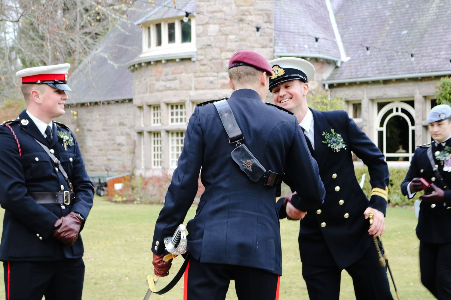 Military officers in formal dress uniforms gather outside a stone mansion during an outdoor ceremony.