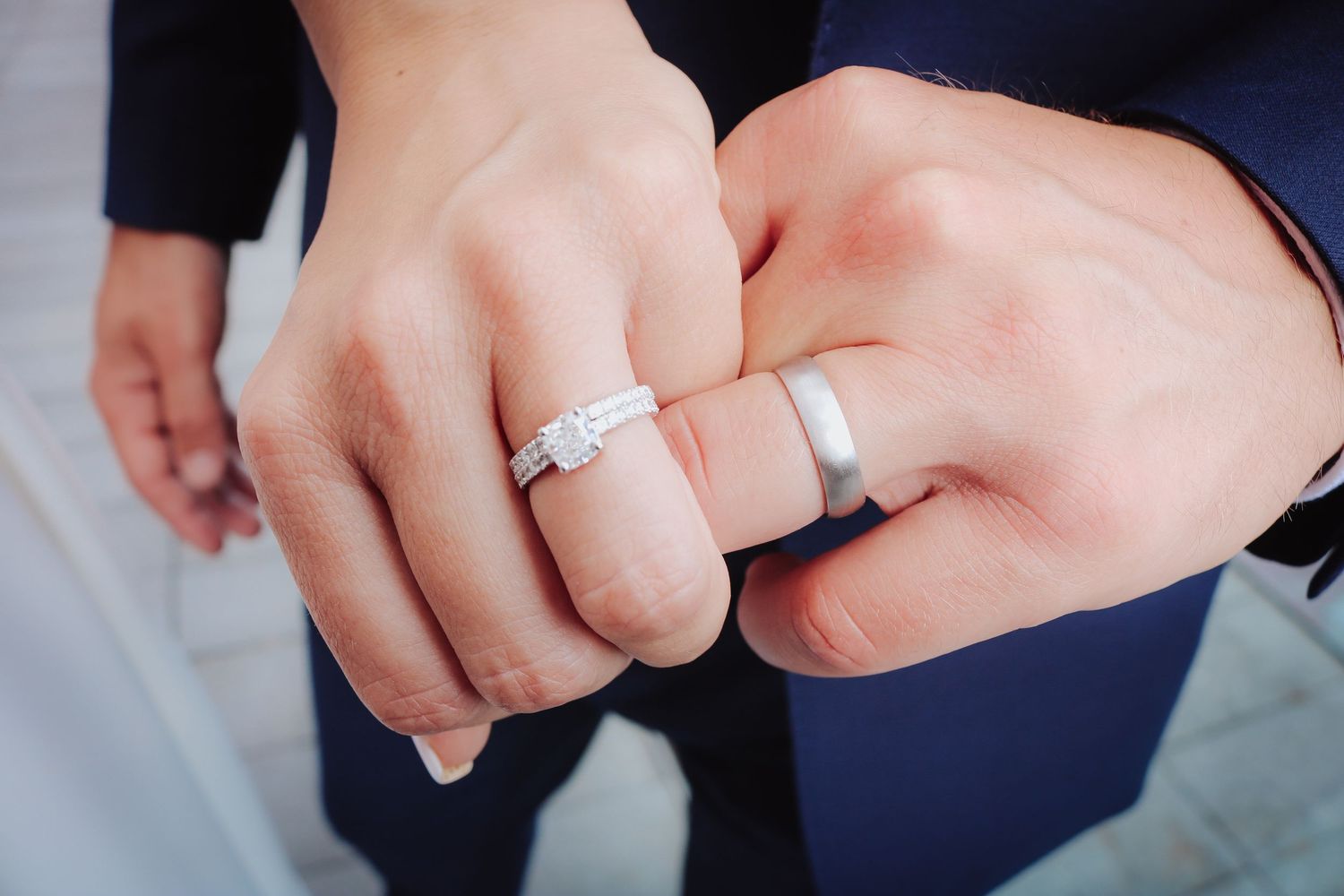 Close-up image of fingers exchanging wedding rings during a marriage ceremony with formal attire.