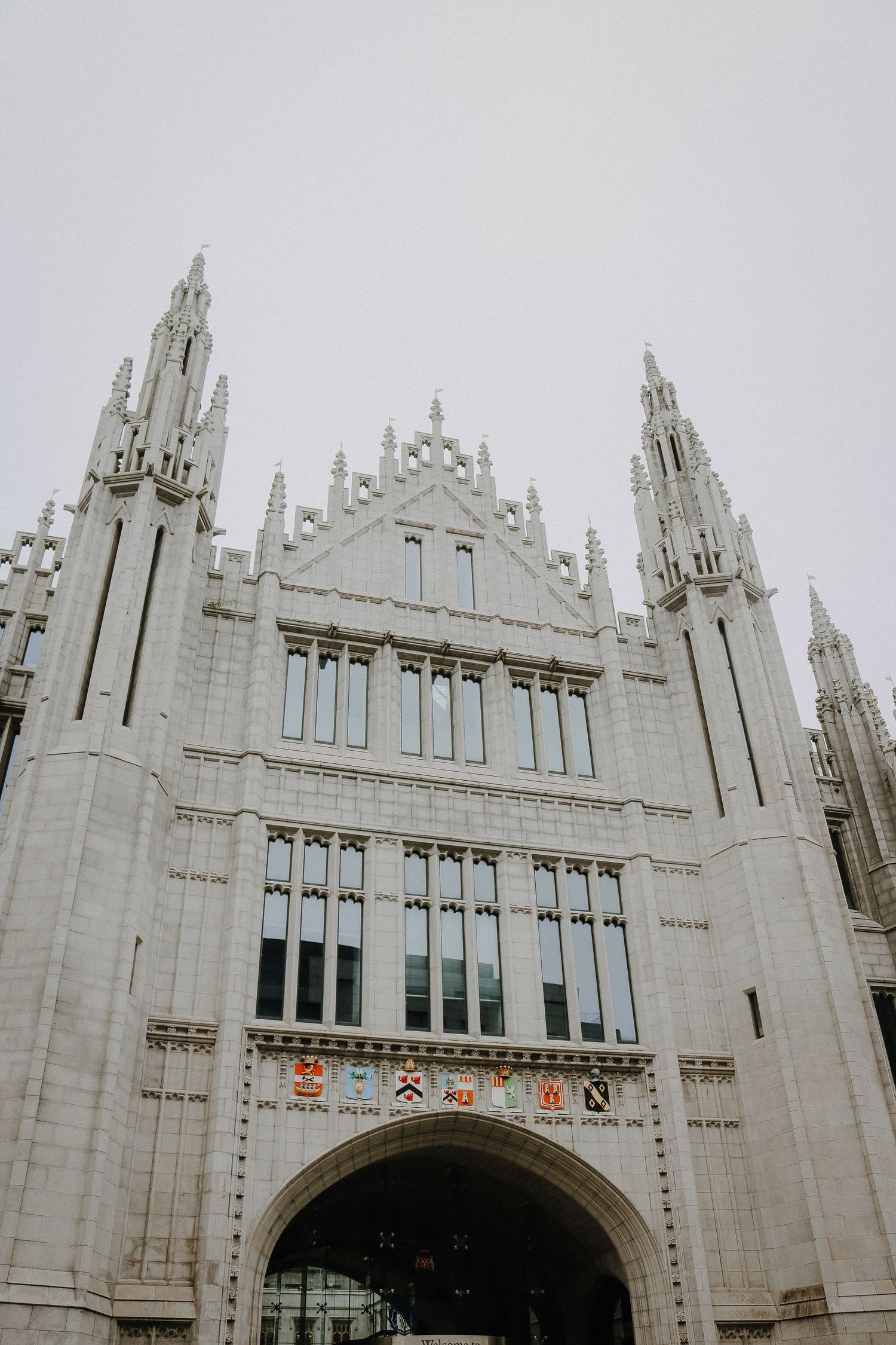 Gothic revival architecture with intricate spires and archway of white stone building in overcast light.