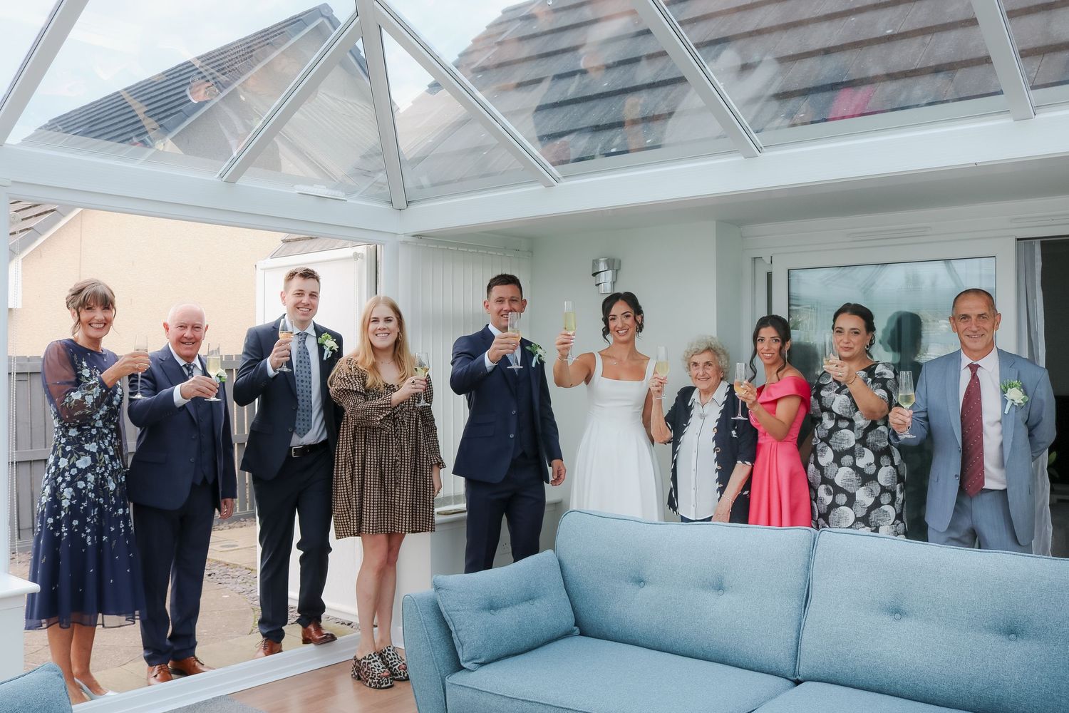 Wedding guests gathered in celebration inside a bright conservatory venue with glass ceiling and modern decor.