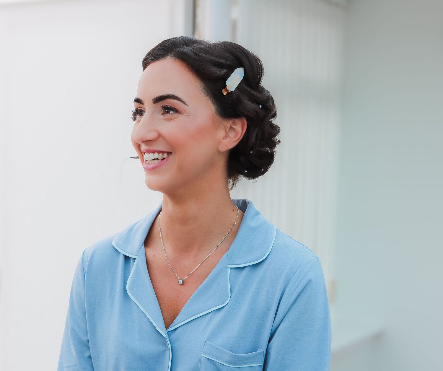 Side profile portrait of someone wearing a light blue collared shirt with dark hair styled in an updo with hair clip.