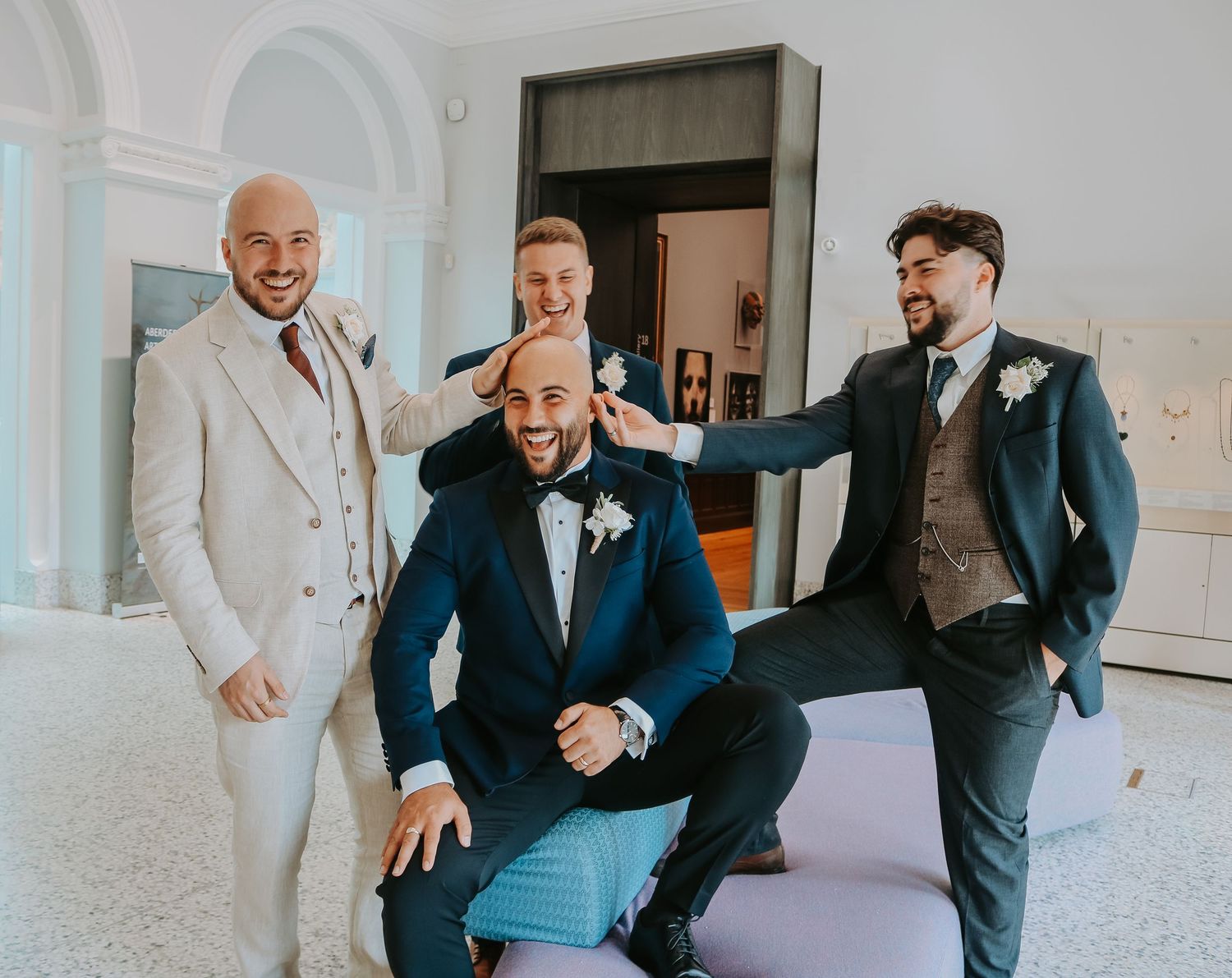 Groomsmen in formal attire sharing a lighthearted moment before the wedding ceremony.