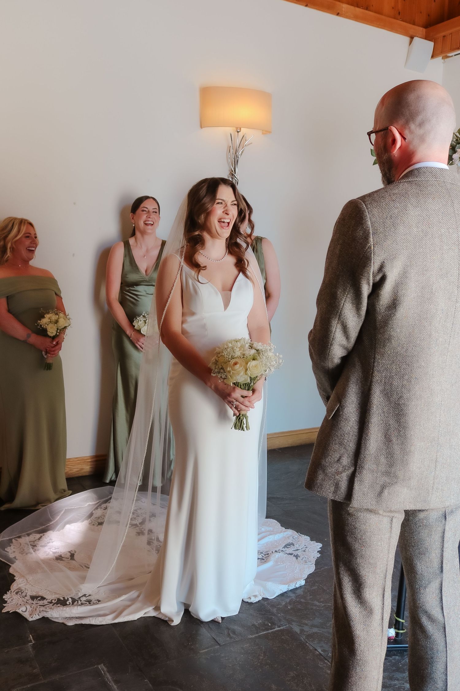 A joyful wedding ceremony scene with bridesmaids in sage green dresses alongside a bride in a flowing white gown.