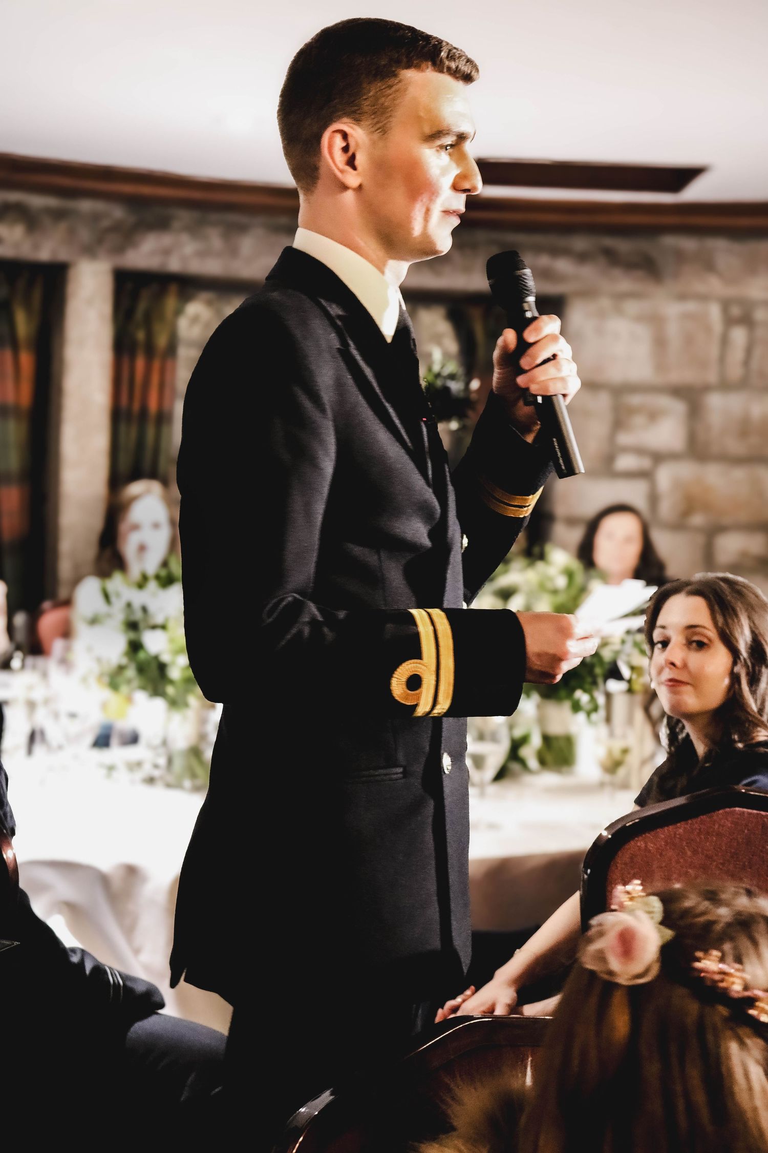 Someone in a formal military dress uniform gives a speech at an elegant wedding reception.