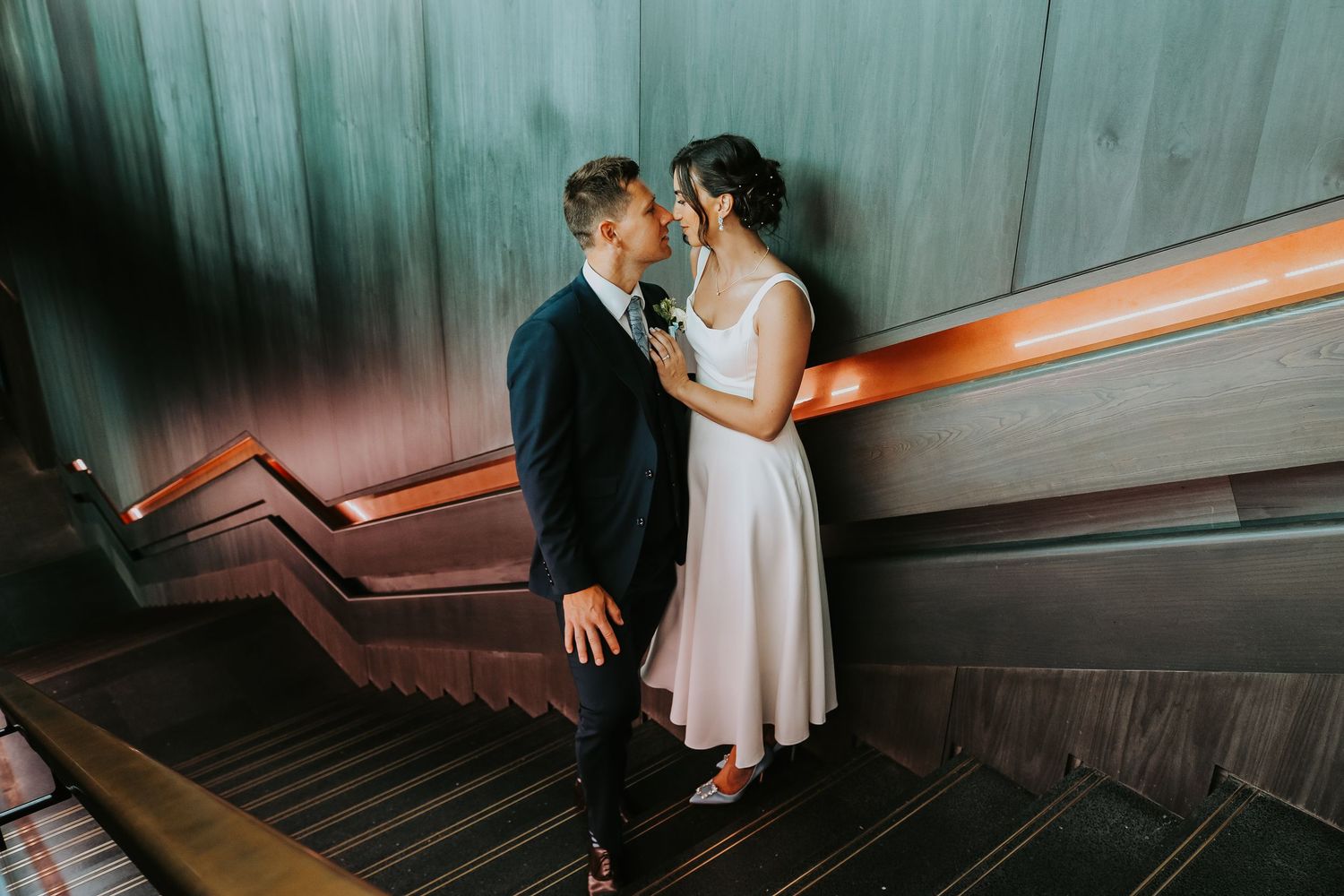 Wedding couple walking down stairs in modern venue with multiple shots showing progression down the steps.