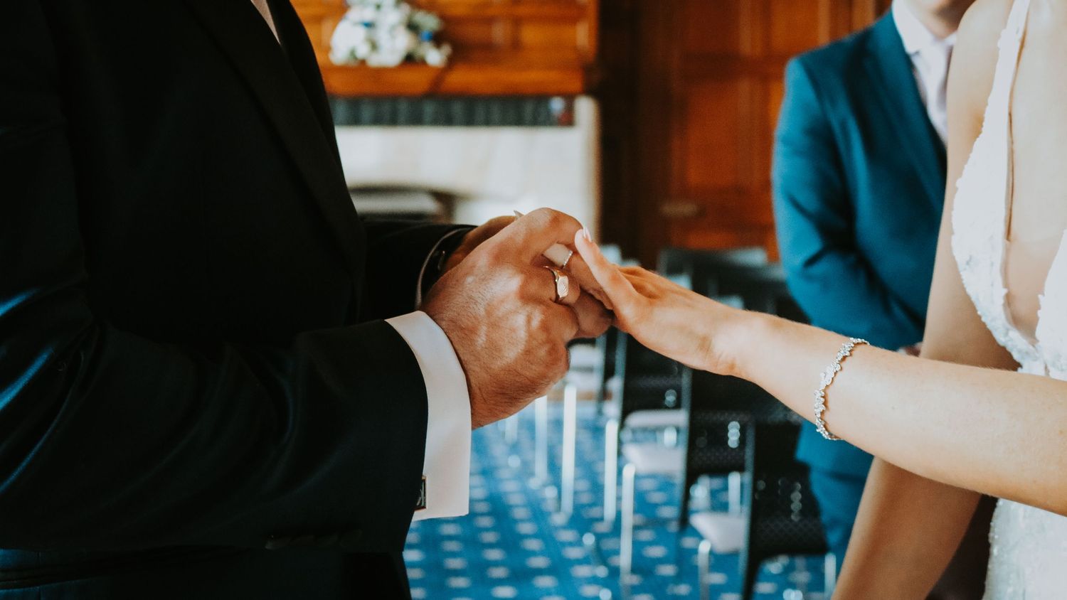Close-up shot of wedding ring exchange between couple's hands during ceremony.