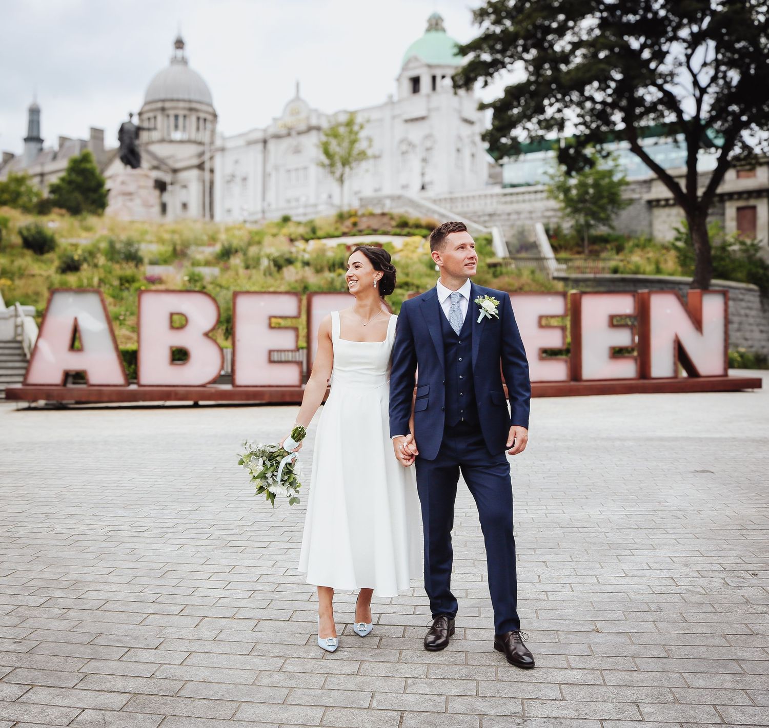 Couple takes romantic photos near large decorative outdoor lettering in Aberdeen, Scotland.