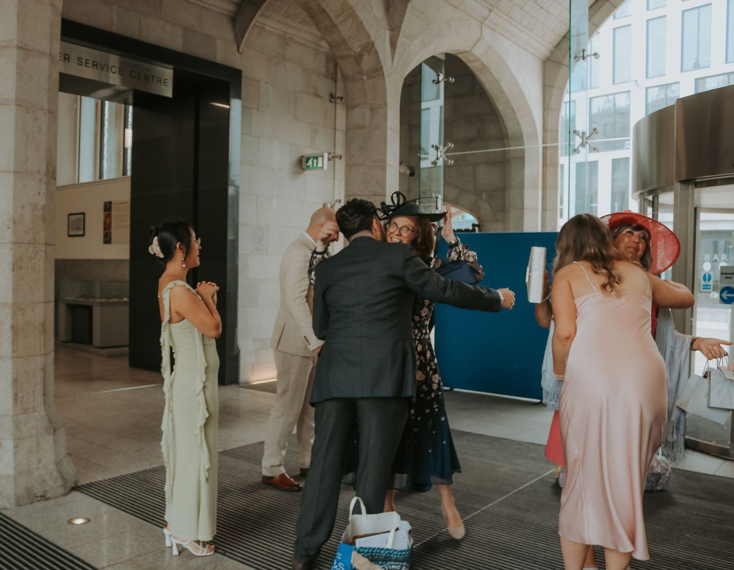 Wedding guests gather under elegant stone archways in formal attire at an upscale venue.