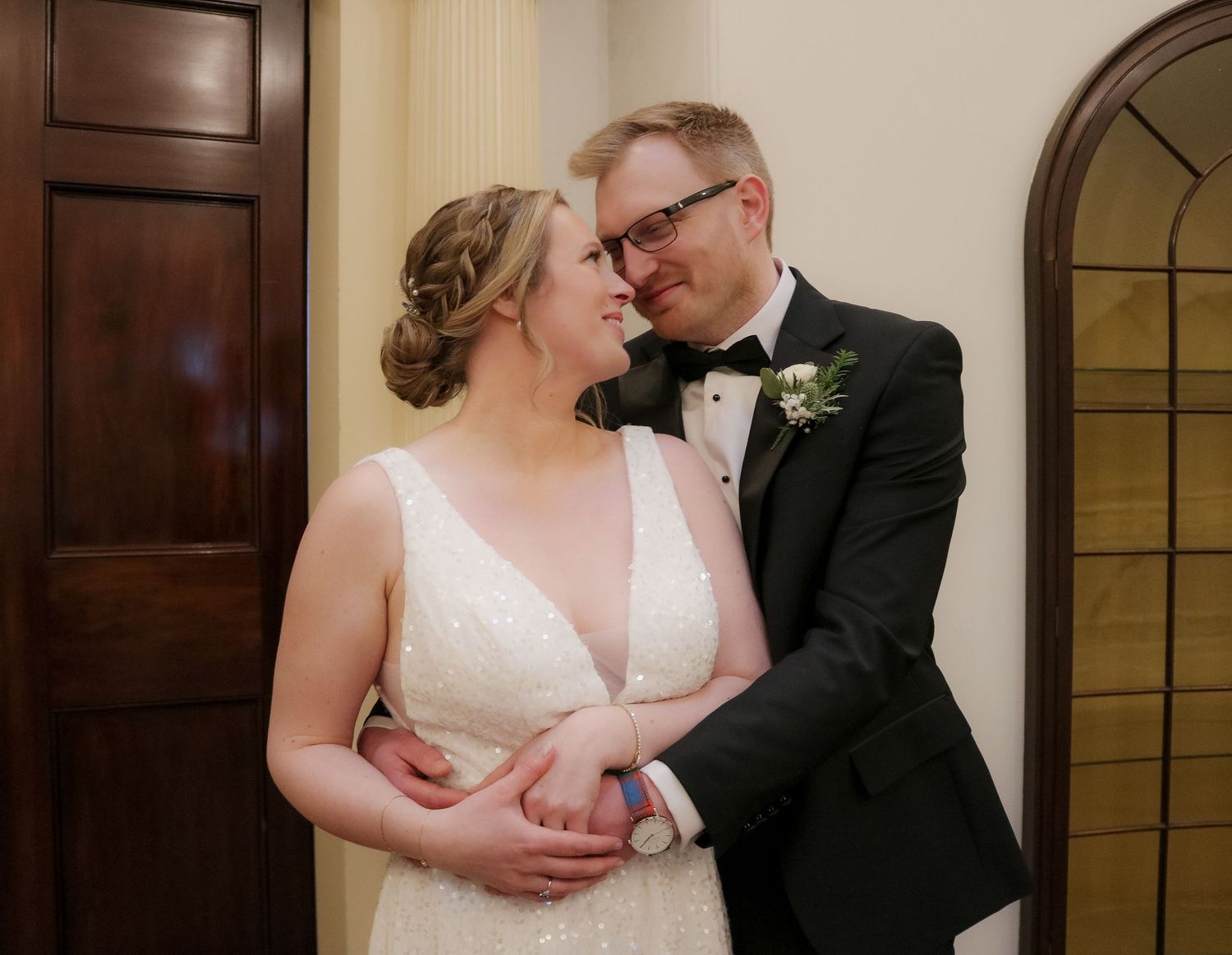 Two elegant wedding-goers share an intimate moment together while dressed in formal black and white attire.