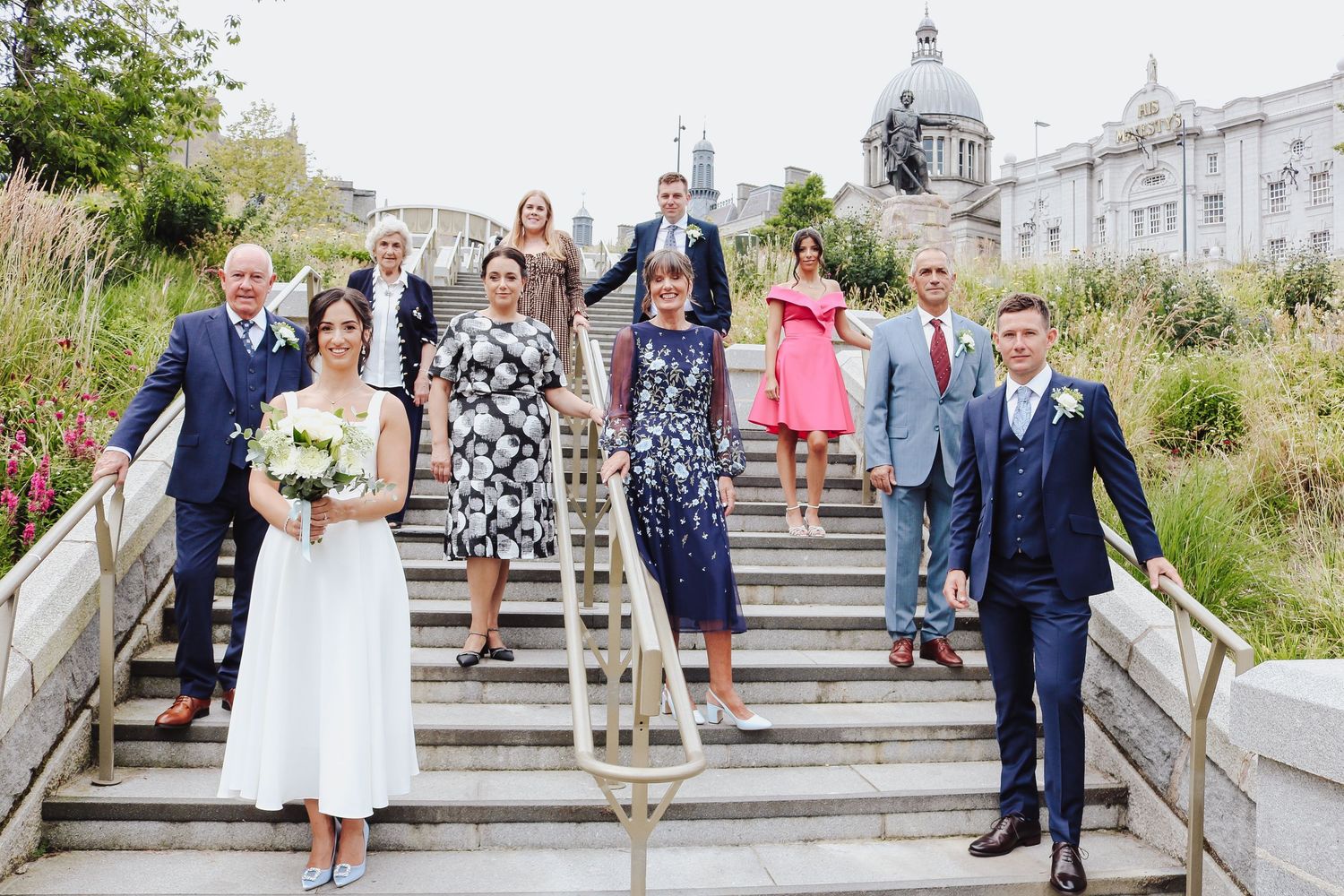 Wedding party descends stone steps during outdoor celebration at historic venue in Aberdeen.
