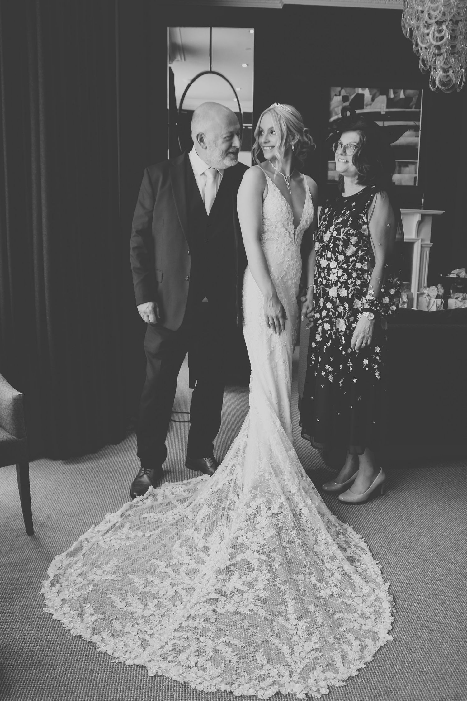 A wedding dress with intricate lace train displayed in an elegant room setting.
