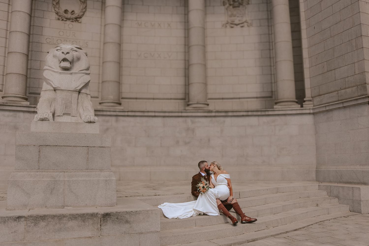 A couple poses together against a grand stone building's exterior walls in a romantic photo series.