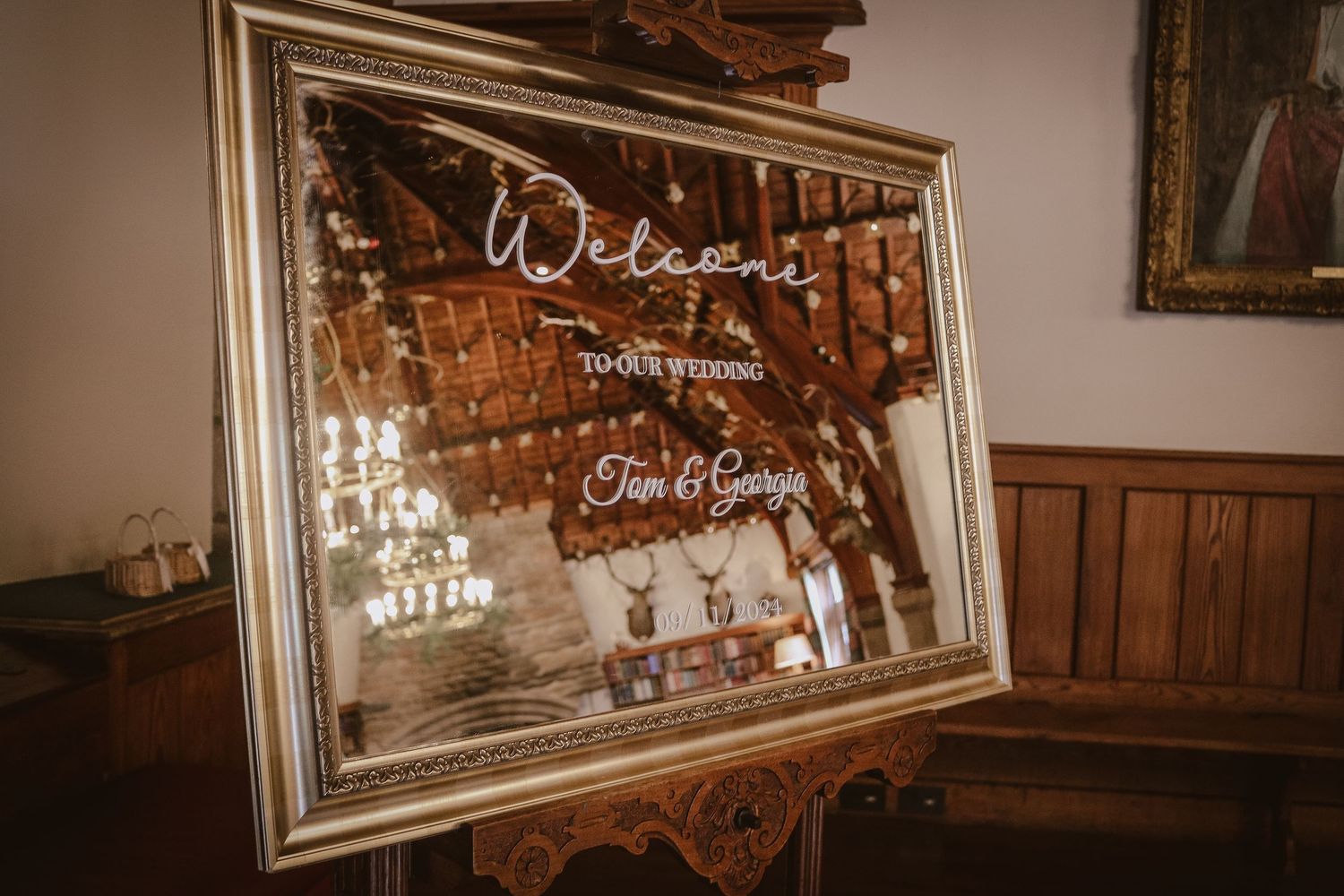 A vintage-style welcome mirror sign with cursive lettering stands elegantly framed against wooden paneled walls.
