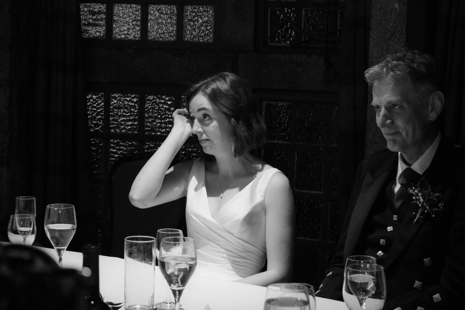 A black and white photo of people sitting at a dinner table with wine glasses in an elegant setting.