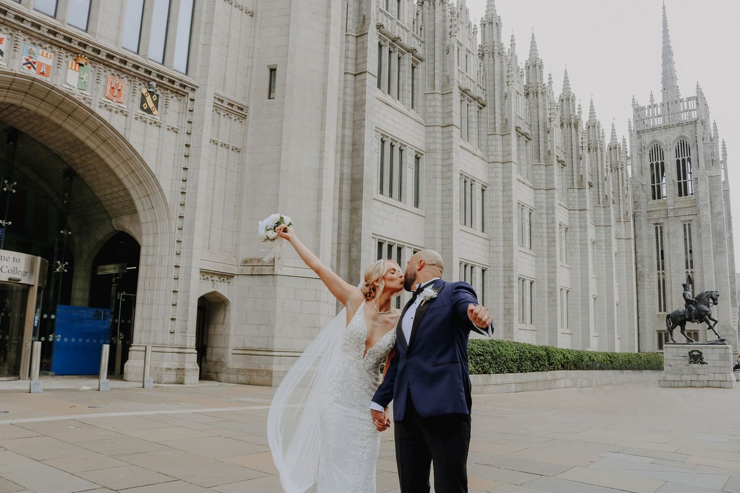 Newlyweds celebrate joyfully outside a grand Gothic Revival cathedral on their wedding day.