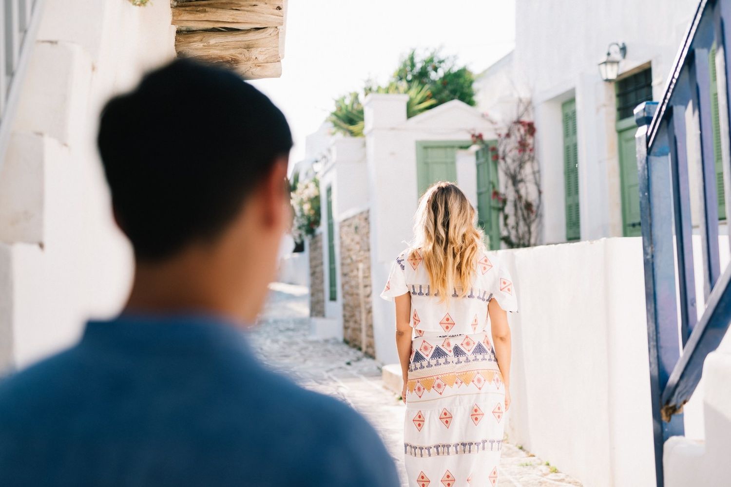 Two people walking through narrow whitewashed Mediterranean alleyways.