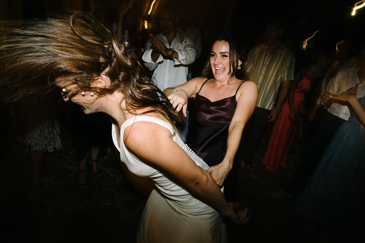 Two dancers showing off wild dance moves with hair flying at a lively party.