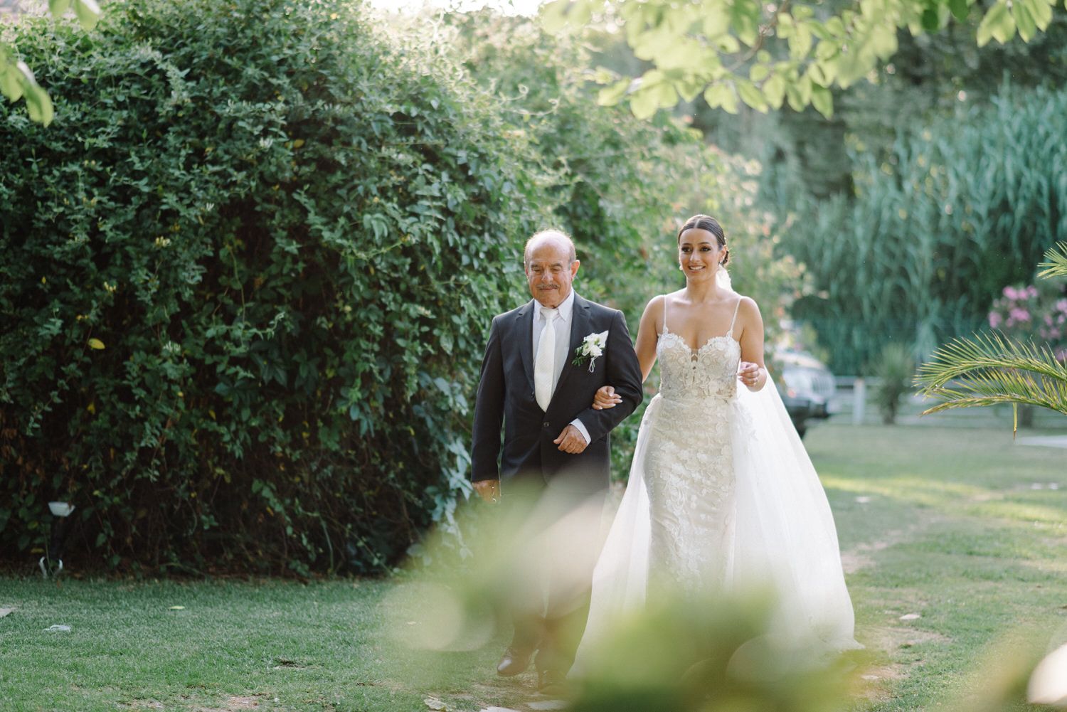 Couple walking through a lush garden setting during their wedding celebration.