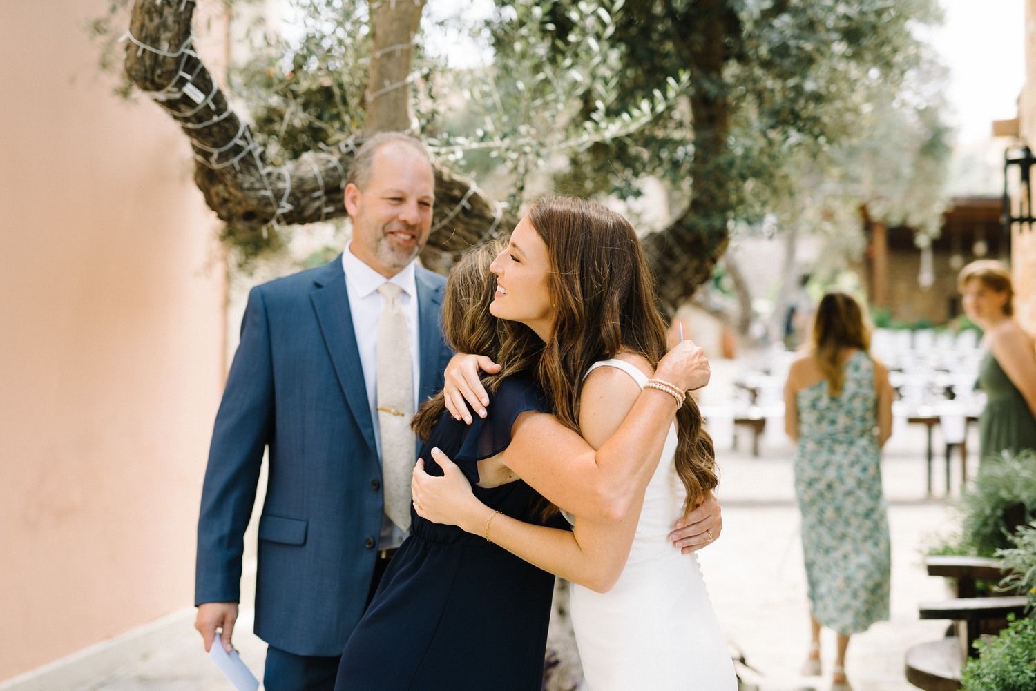 Wedding couple sharing a joyful moment outdoors near a pink wall.