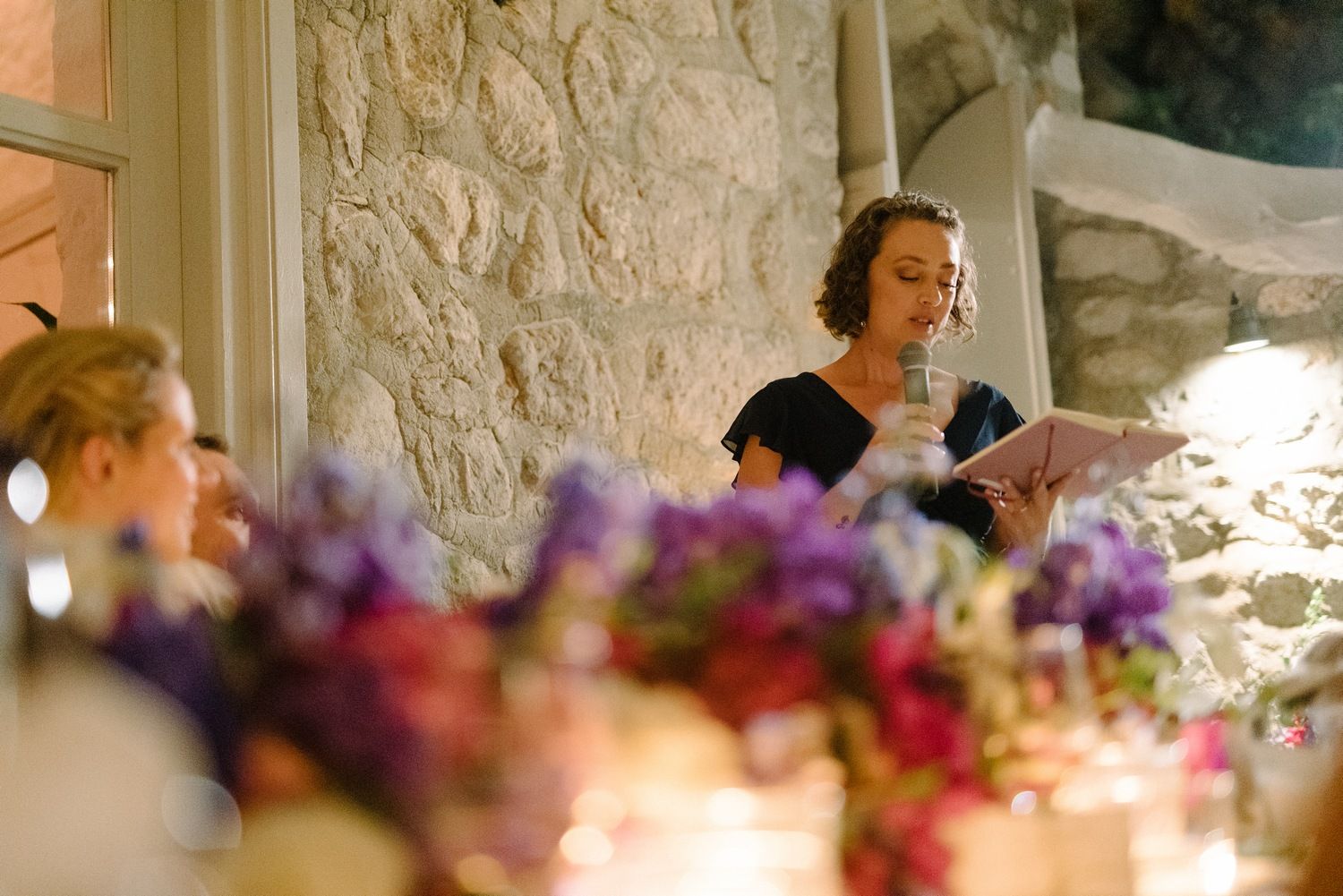Wedding reception speech being delivered over elegant floral table decorations.