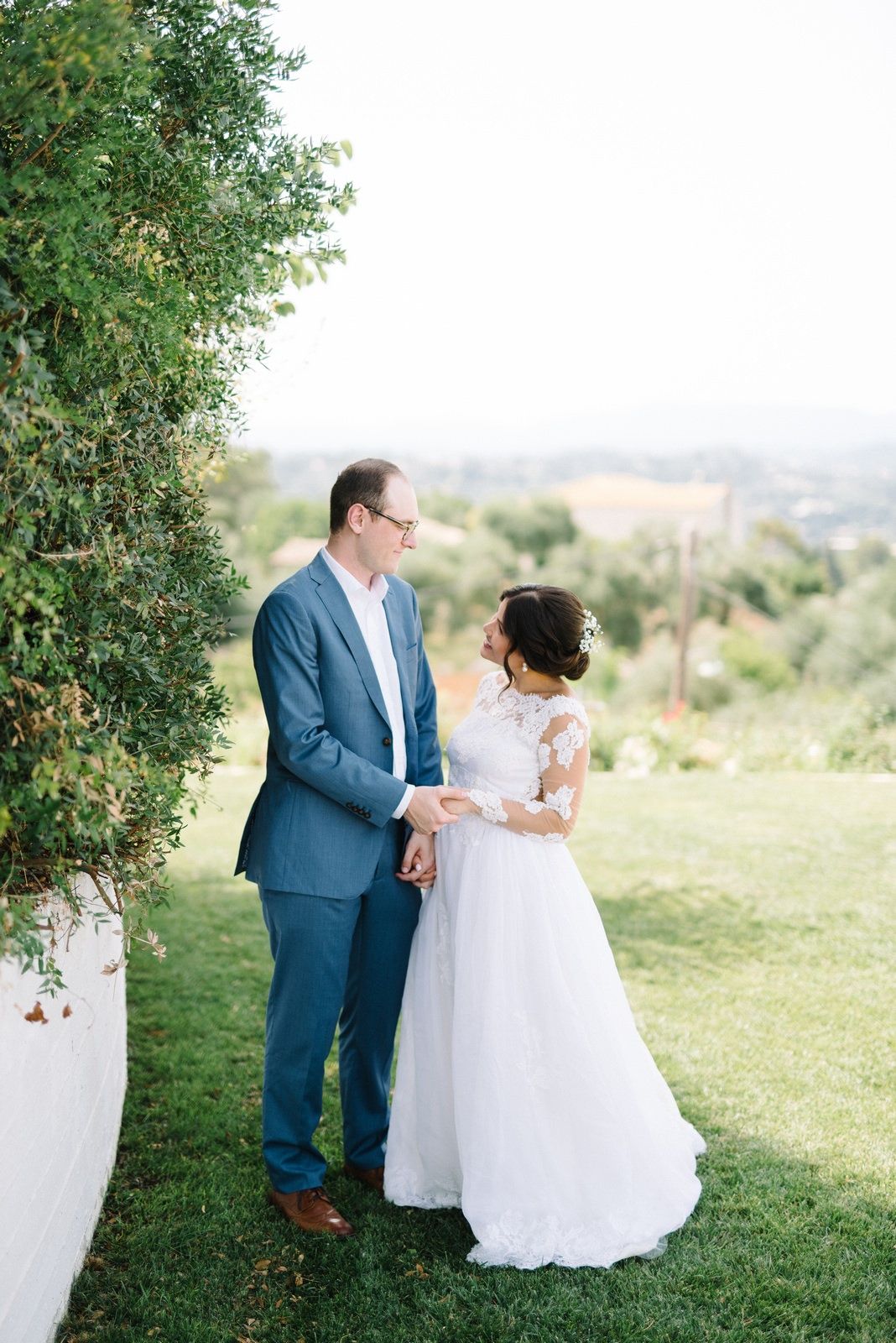 Romantic outdoor wedding portrait with couple standing on green lawn.