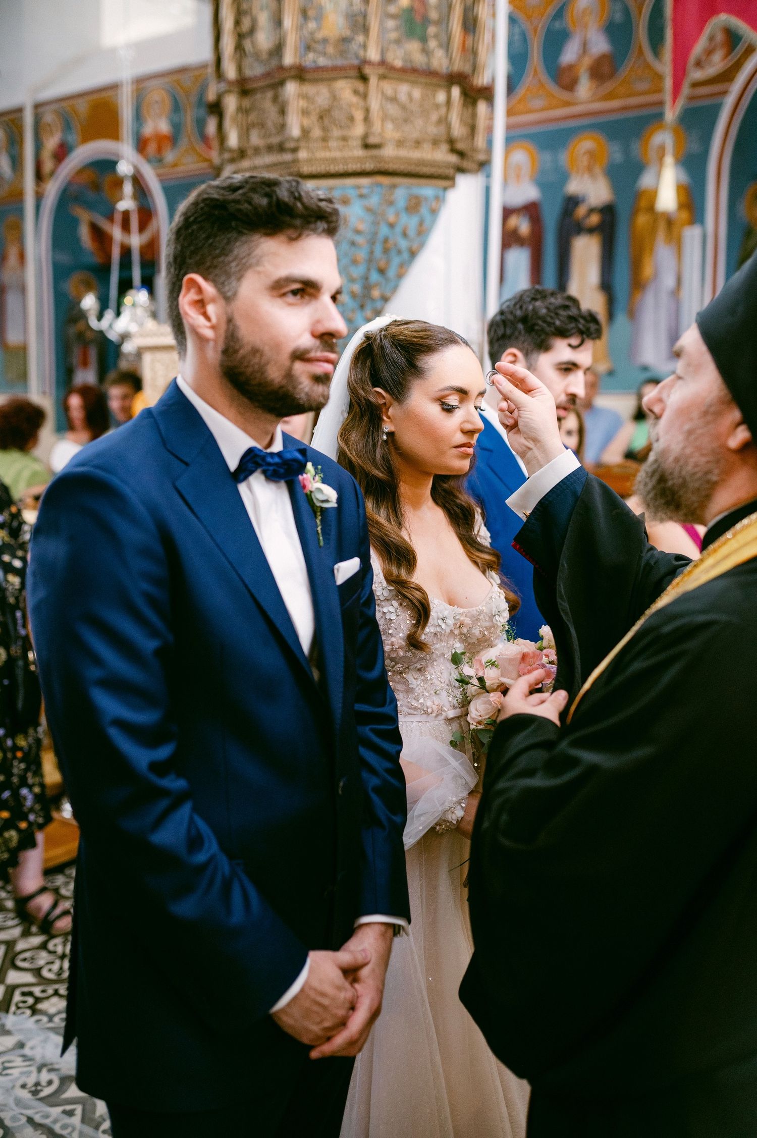 Orthodox wedding ceremony in ornate church interior with traditional decoration and religious iconography.