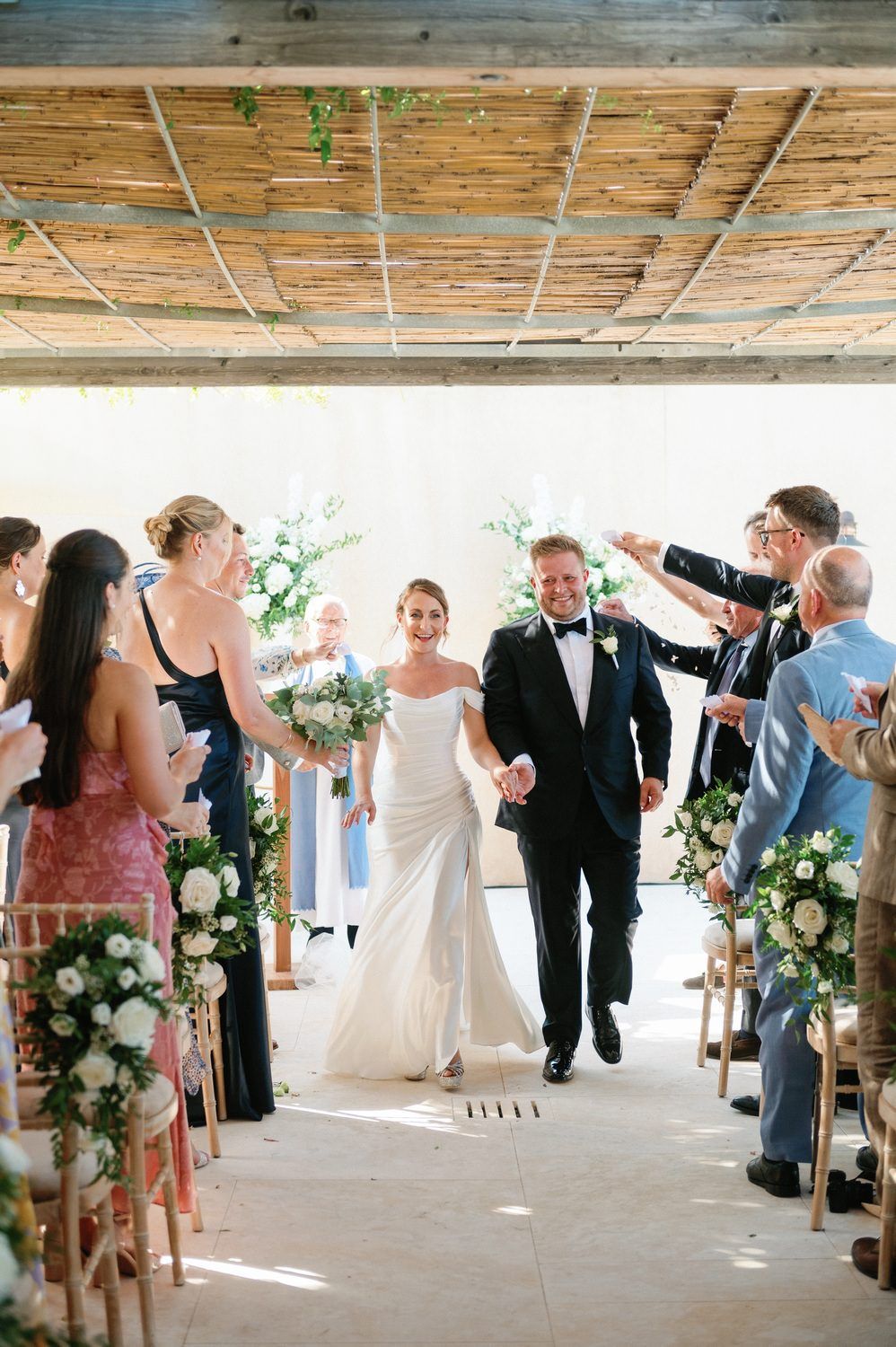 Newlyweds walk down the aisle while guests celebrate during their recessional.