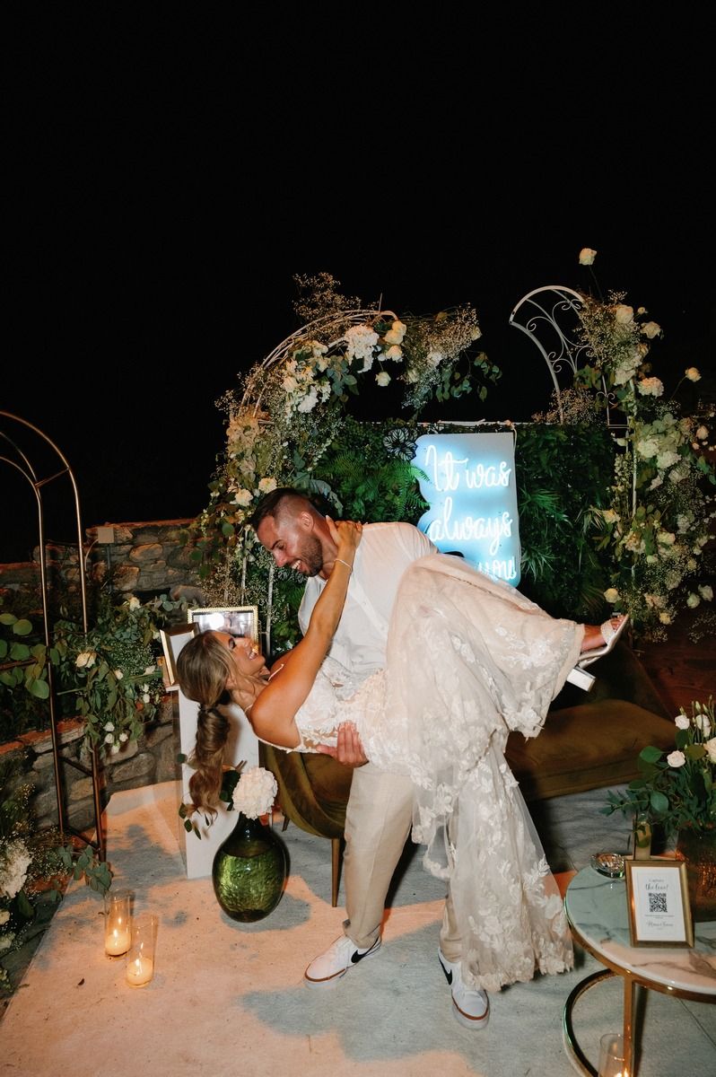 Romantic dance dip during wedding celebration under floral arch and garden lights.