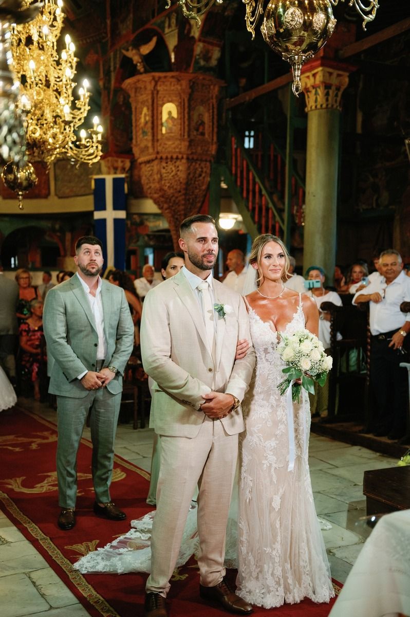 Orthodox church wedding ceremony with ornate gold chandeliers and traditional decor.