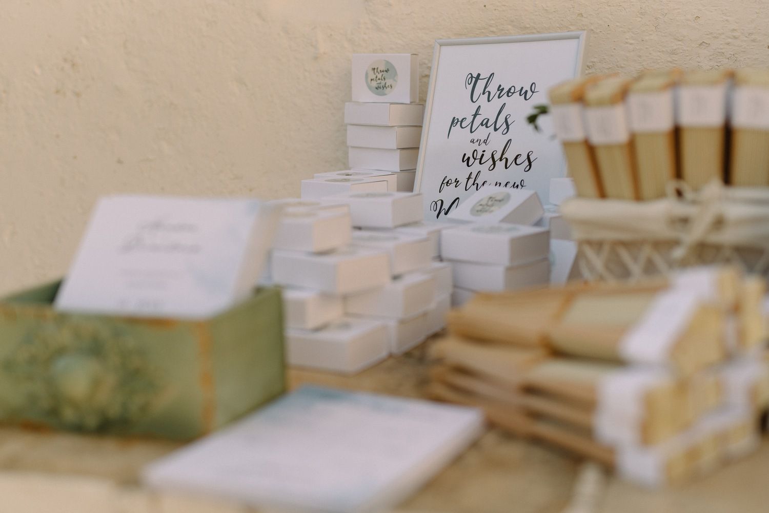 Elegant white wedding stationery and favor boxes arranged on display table.