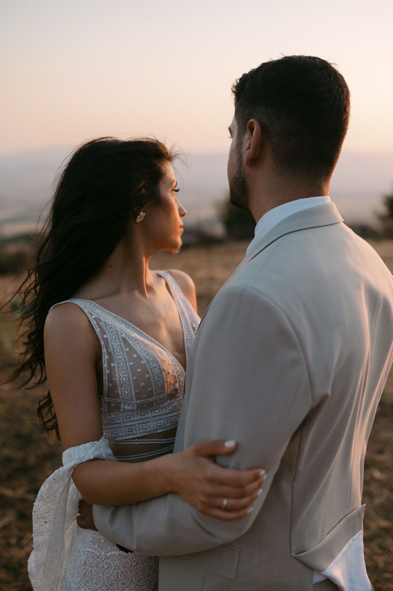 Romantic couple embraces during golden hour sunset photoshoot in a scenic outdoor setting.