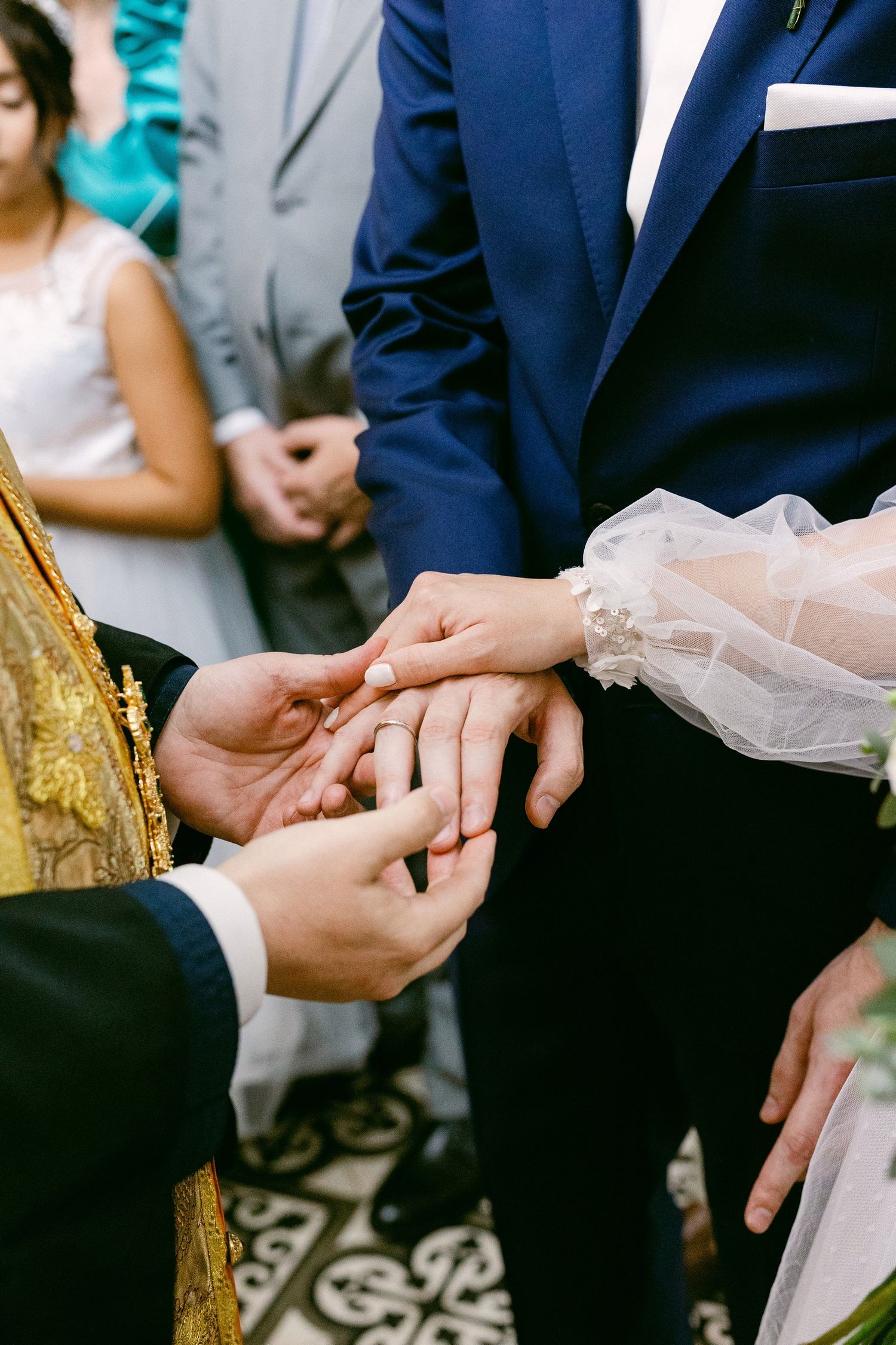 Religious ceremony shows hands exchanging wedding rings during a traditional marriage service.
