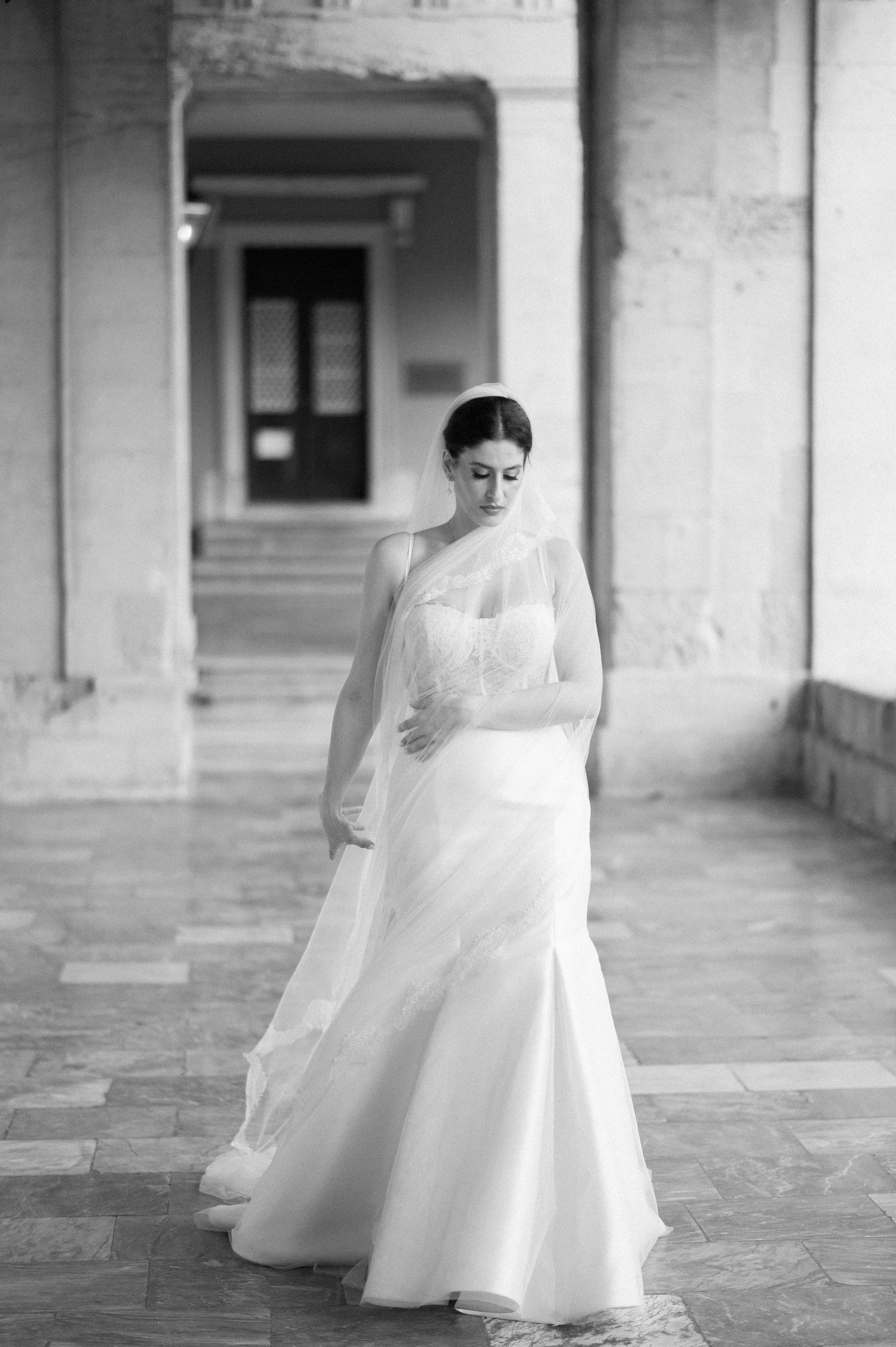 A sequence of black and white photos showing a bride in a flowing white gown twirling in an elegant stone corridor.