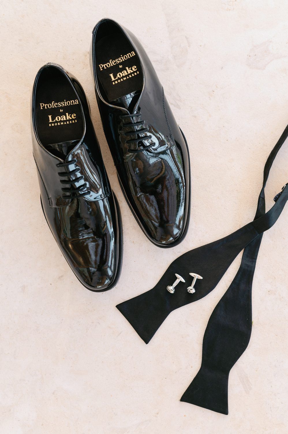 A sequence of four similar shots showing shiny black patent leather dress shoes with a black bow tie on white surface.
