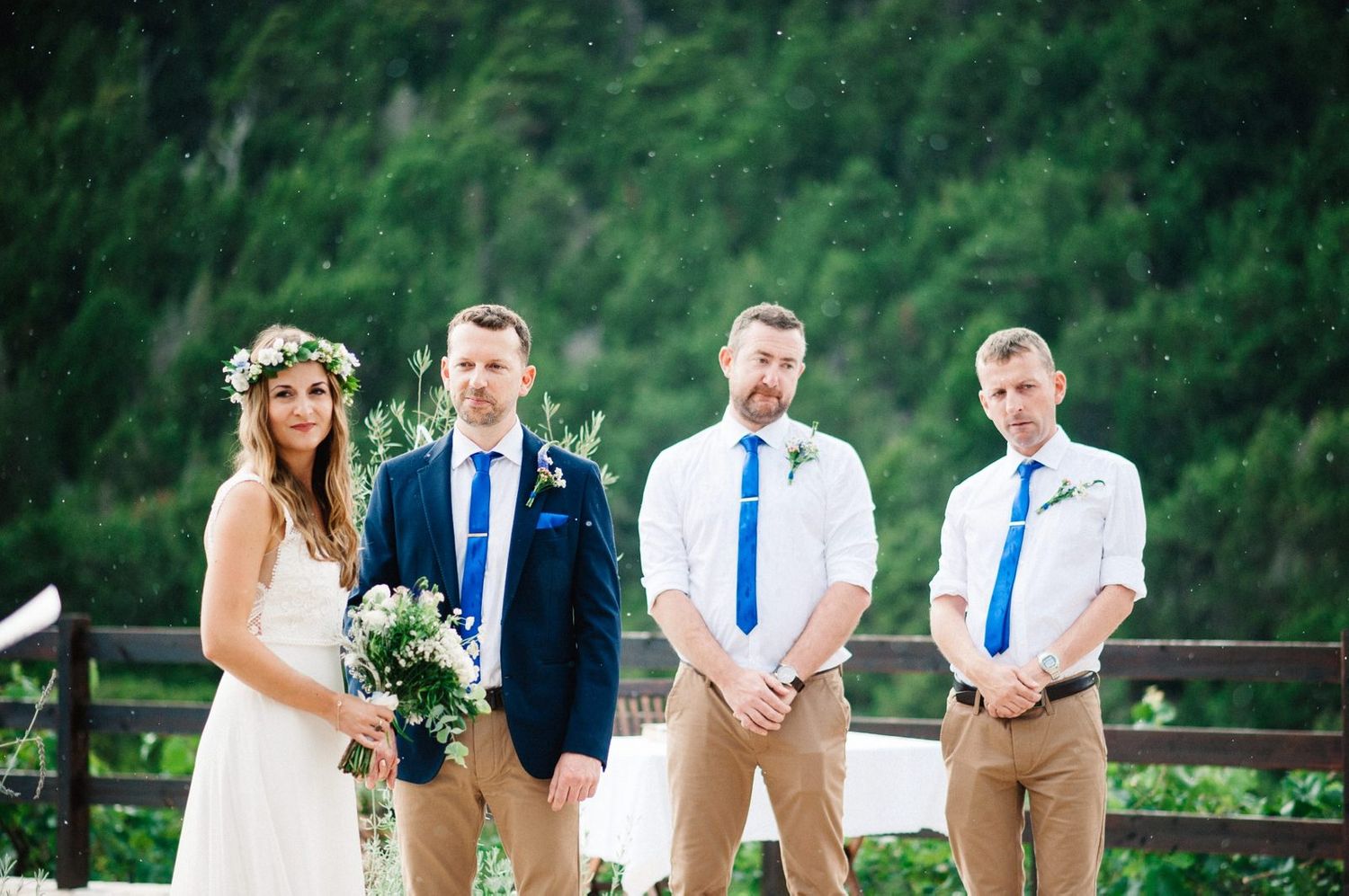 Wedding party poses outdoors with mountains and forest in background.