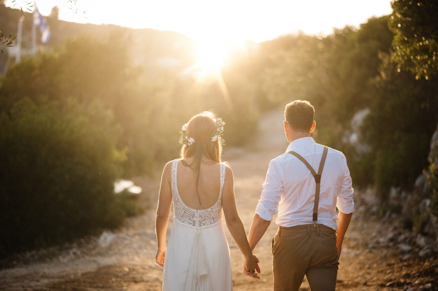 Couple walking hand in hand into the sunset on a Mediterranean coastal path.