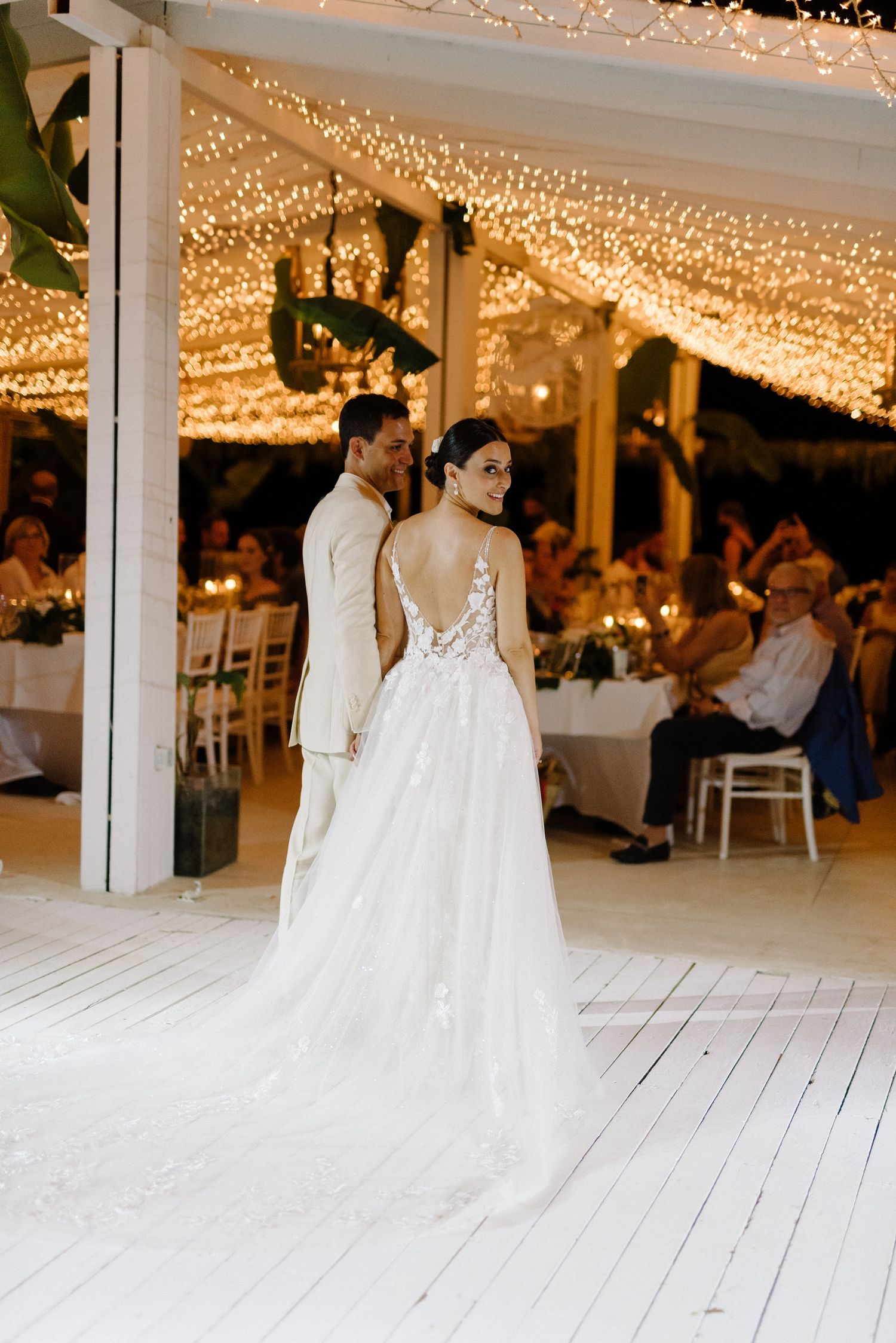 A romantic wedding reception venue with twinkling fairy lights on the ceiling and white wooden floors creating a magical ambiance.