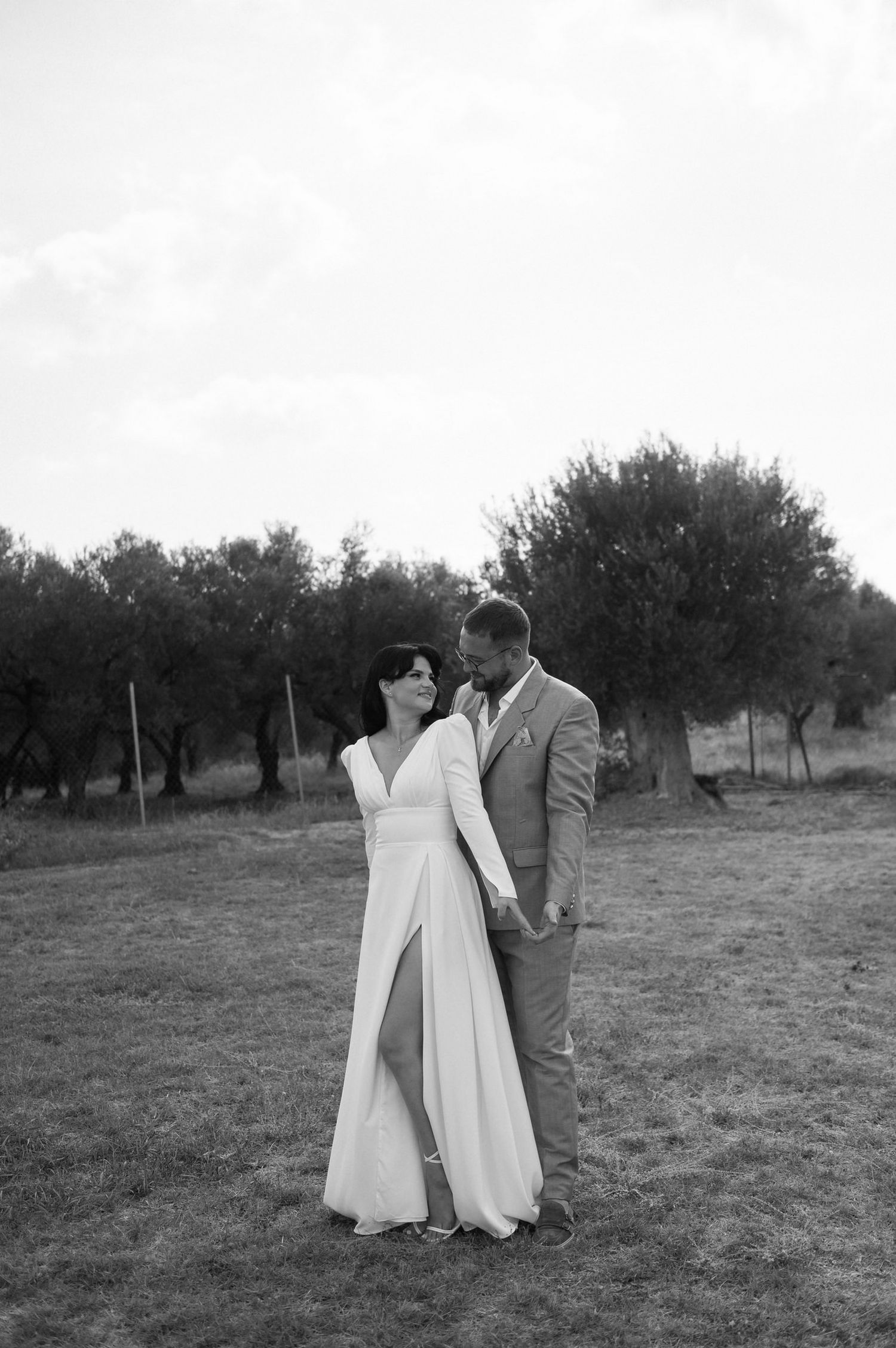 Black and white wedding photos capture tender moments between newlyweds in a rustic outdoor setting.