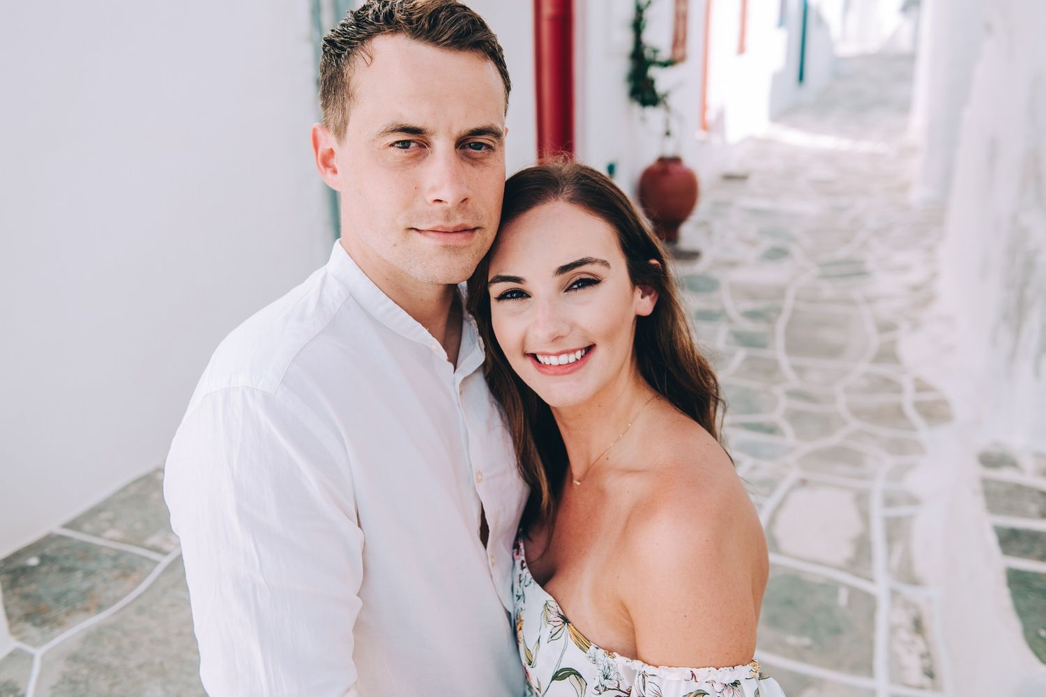 A joyful portrait captured against white Mediterranean walls in natural lighting.