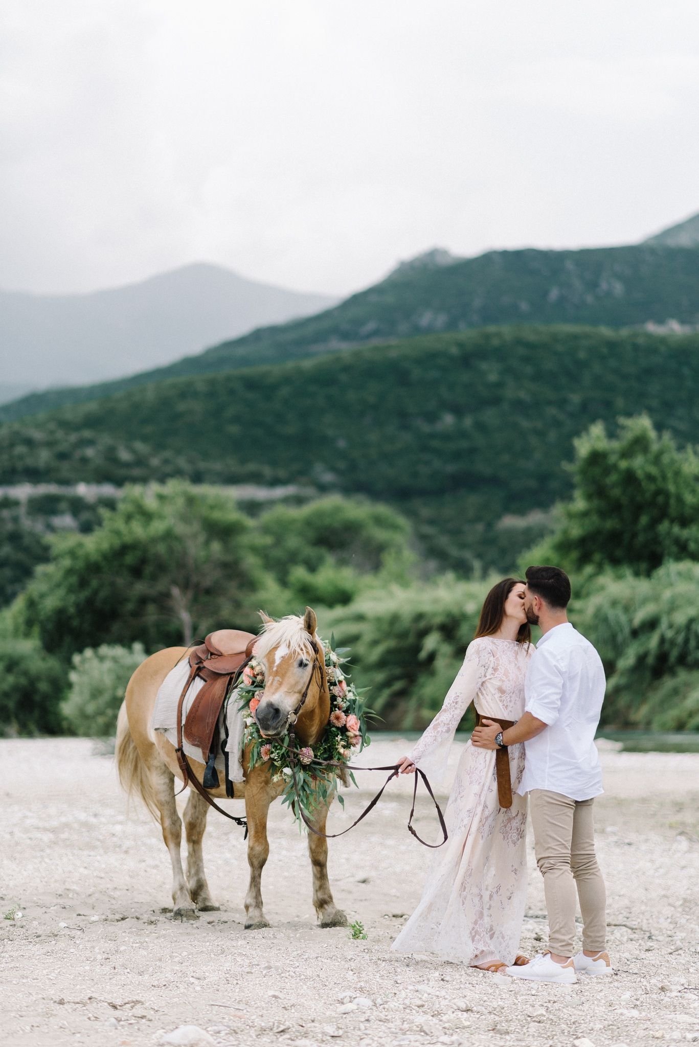 Romantic moment with decorated horse in foreground against mountain backdrop.