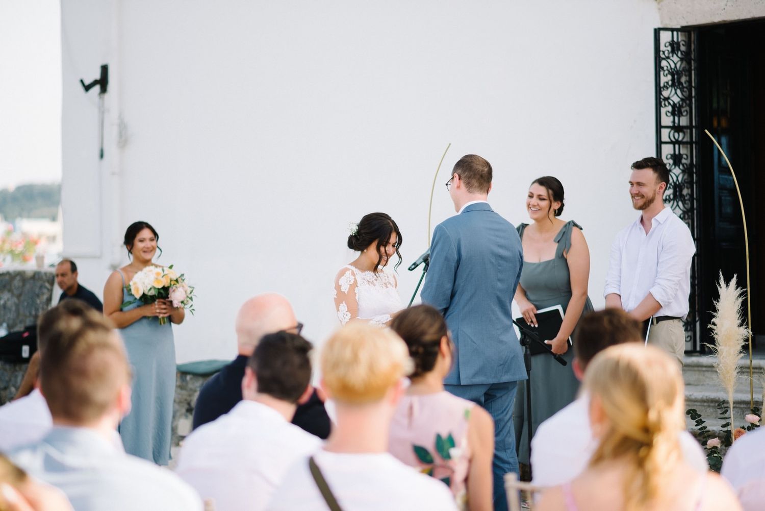 Wedding ceremony taking place outdoors with guests watching the couple exchange vows.