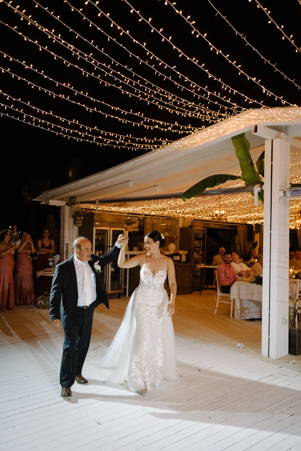 Wedding reception dance under a canopy of twinkling fairy lights on a white deck.