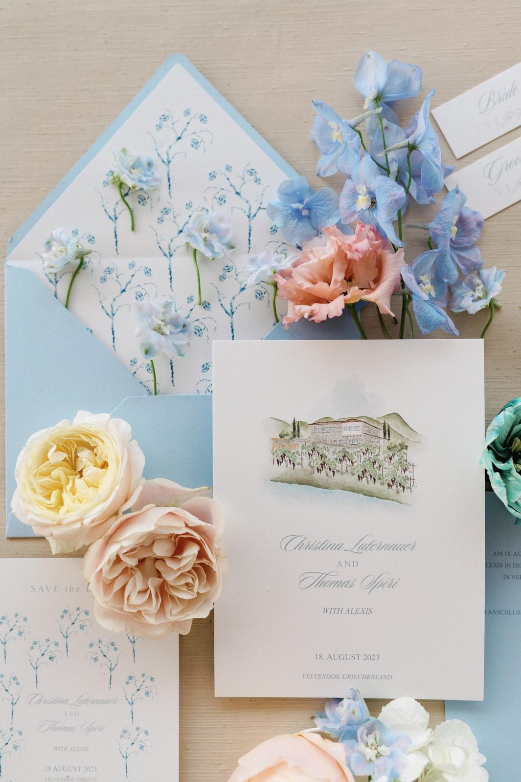 Elegant wedding invitation suite with blue and peach flowers, featuring delicate floral patterns and watercolor artwork.