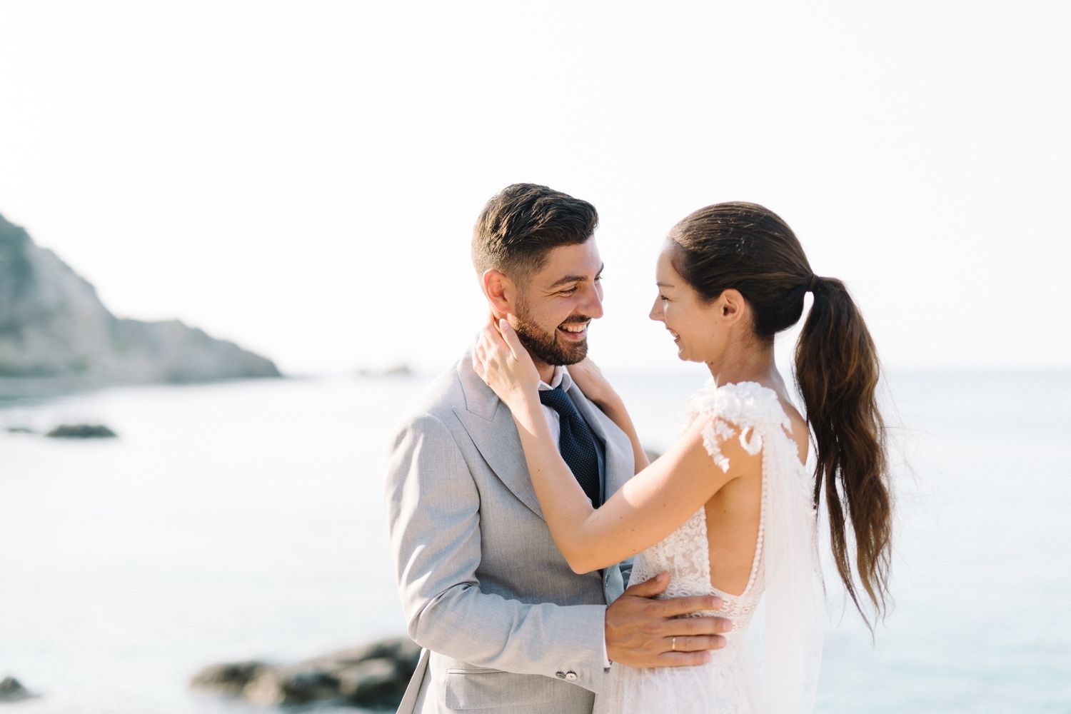 A romantic beach wedding photoshoot featuring a couple embracing against a coastal backdrop.