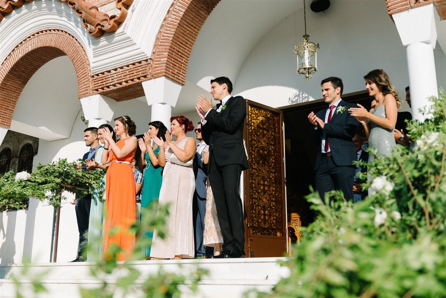 Wedding party celebrating on a Mediterranean-style veranda with brick arches and columns.